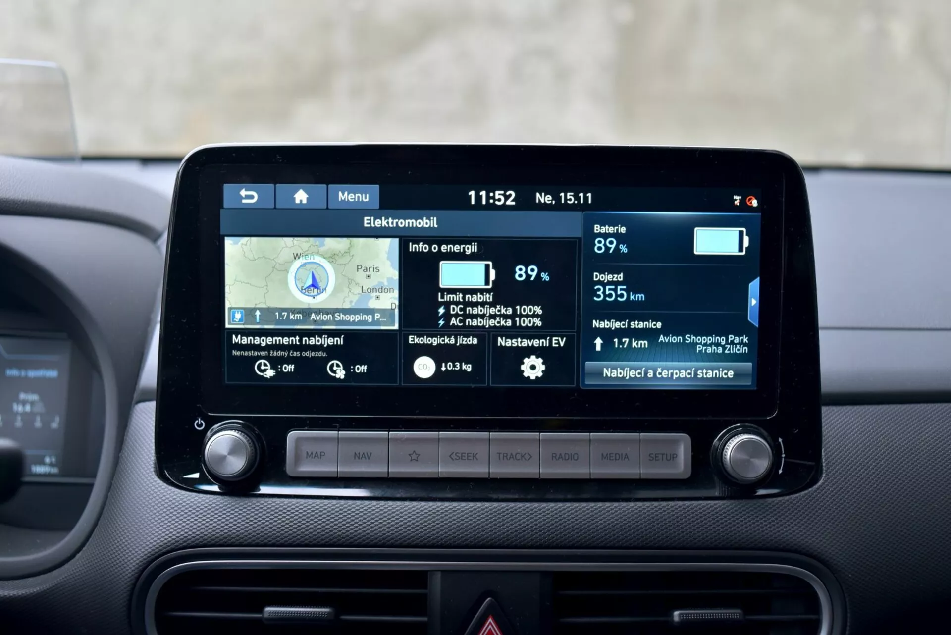 Cruscotto centrale di Hyundai Kona Elettrica 2021 con schermo touch infotainment da 8 pollici che mostra la navigazione e le caratteristiche del veicolo elettrico, inclusi un indicatore della batteria all'89%, autonomia di 355 km, consumo di energia e stazioni di ricarica vicine.