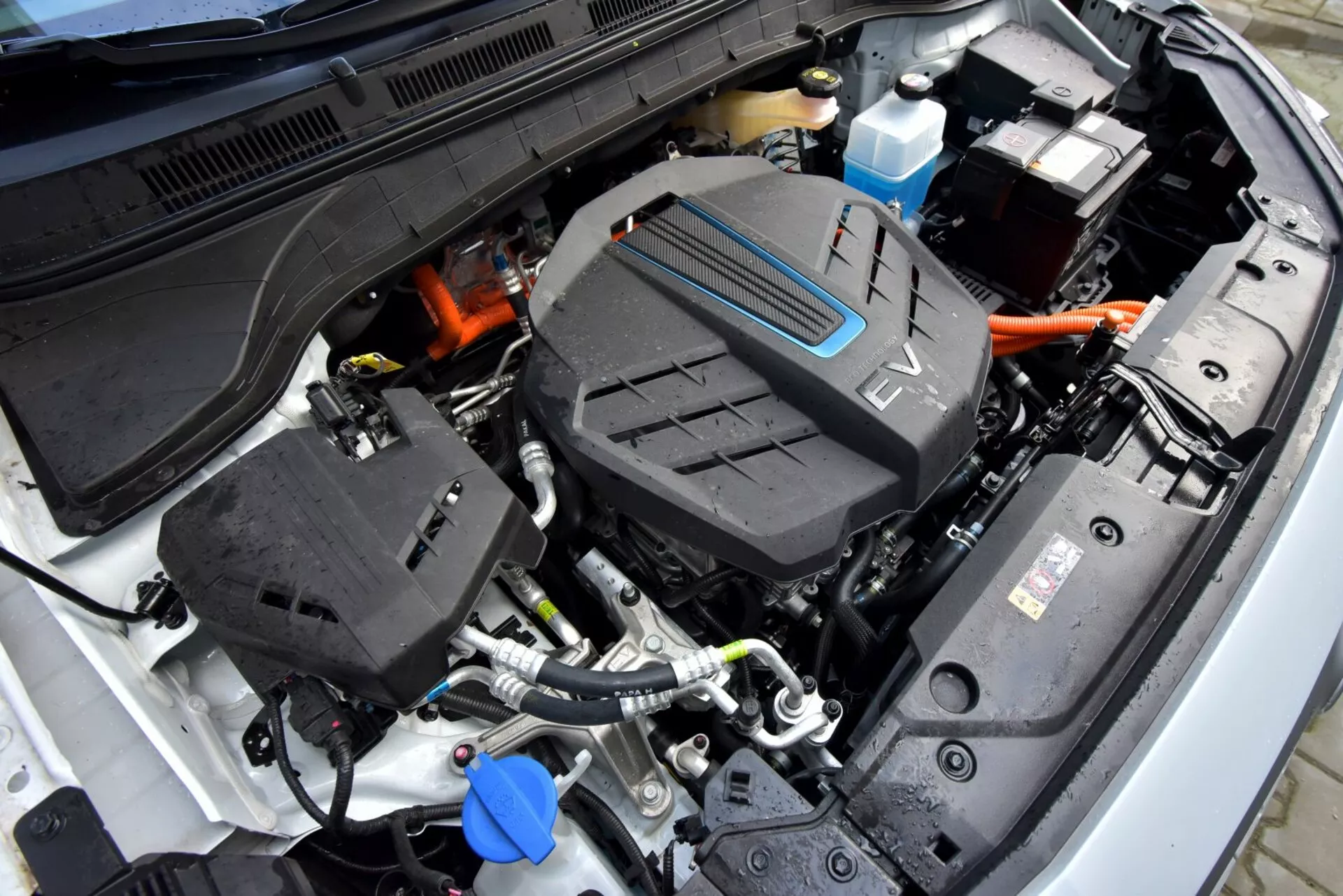 Vista ravvicinata del vano motore aperto della Hyundai Kona 2021 (Kona Elektro) che evidenzia il gruppo propulsore centrale e i cavi ad alta tensione, illustrando la tecnologia del veicolo elettrico di questo modello.
