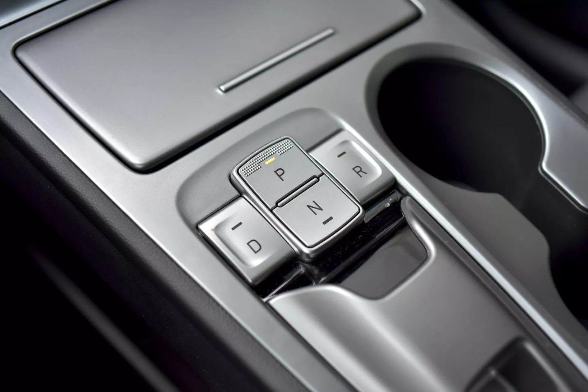 Vista ravvicinata del selettore di marcia della trasmissione automatica di Hyundai Kona 2021 dal design elegante, con etichette 'P', 'R', 'N', 'D' e finiture premium, vista da un angolo sopraelevato