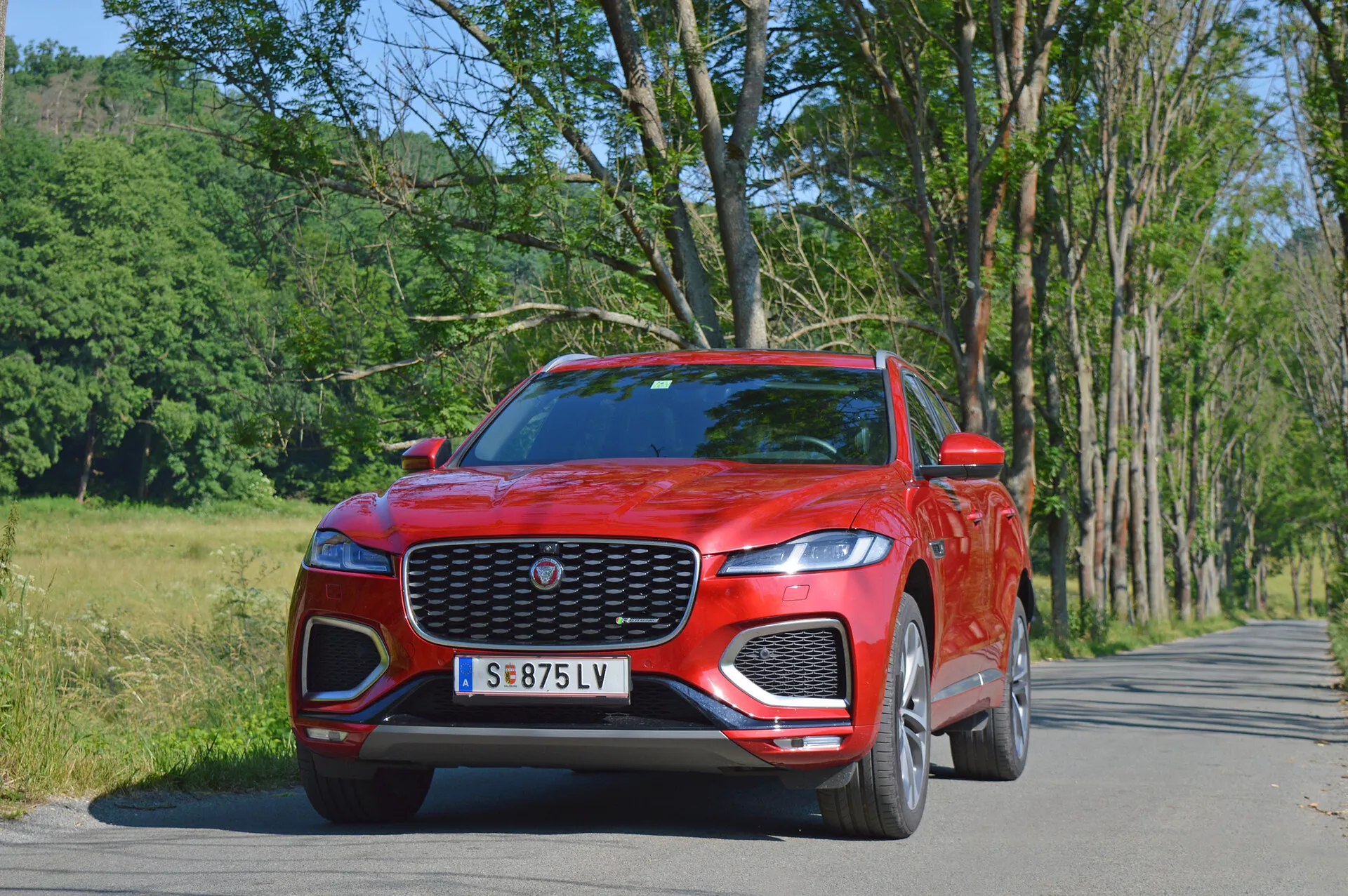 SUV di lusso Jaguar F-Pace 2021 in elegante argento, catturato durante una dinamica guida in città, evidenziando la sua distintiva griglia anteriore, i fari a LED e i cerchi in lega sportivi.