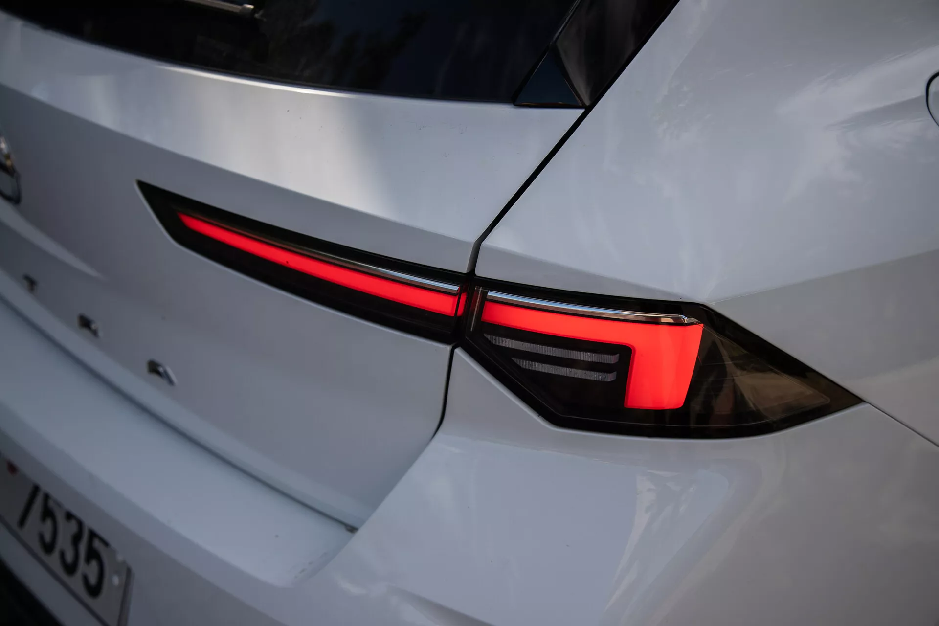 Primo piano della luce posteriore sinistra dell'Opel Astra 2022 che mostra un design LED elegante e l'integrazione nella carrozzeria bianca con un'estetica sportiva