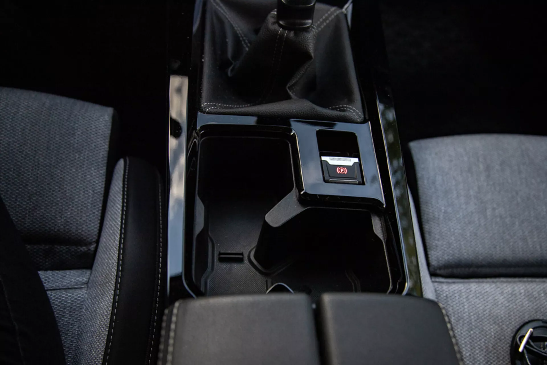 Dettaglio della console centrale di Opel Astra 2022 che mostra vano portaoggetti aperto, tappezzeria in tessuto, leva del cambio manuale in pelle forata, porta USB e illuminazione interna