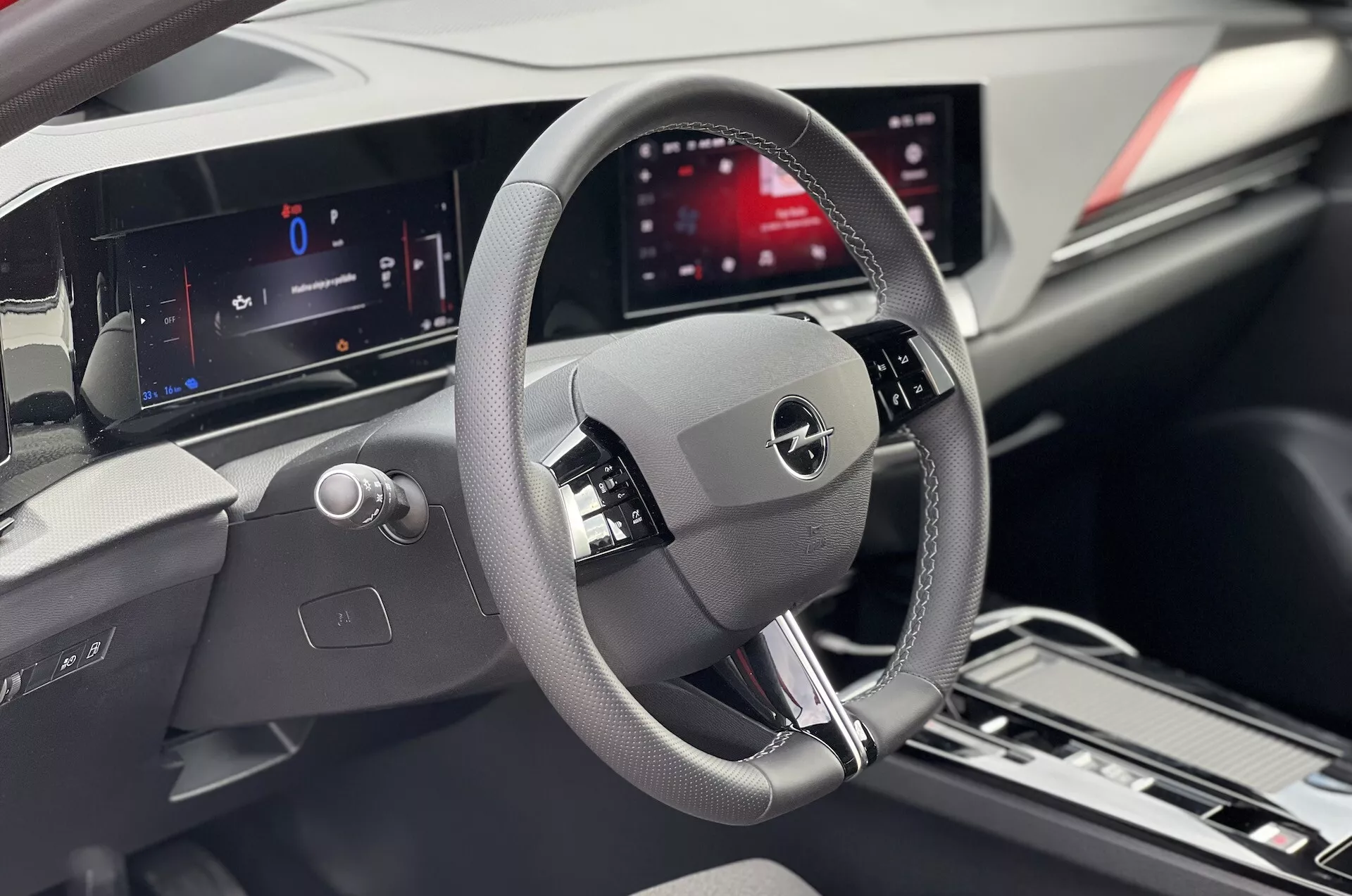 Vista interna di una Opel Astra 2022 focalizzata sull'area del conducente con dettagliato volante, cruscotto digitale e display centrale dell'infotainment