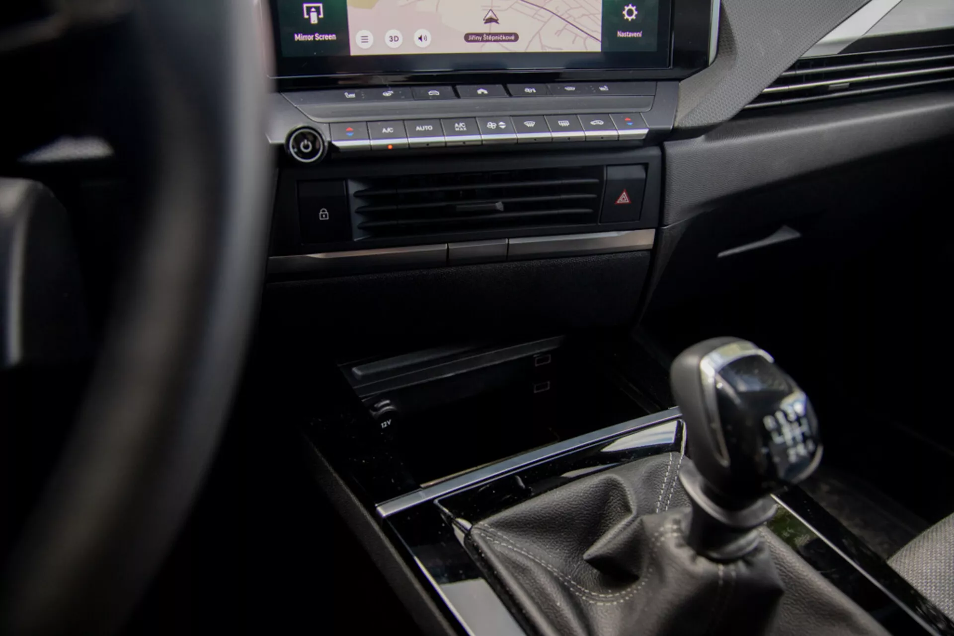 Vista interna dell’Opel Astra 2022 focalizzata sulla consolle centrale e sul cambio manuale dalla prospettiva del guidatore, mostrando il volante, elementi di design di lusso e sistema di infotainment moderno.