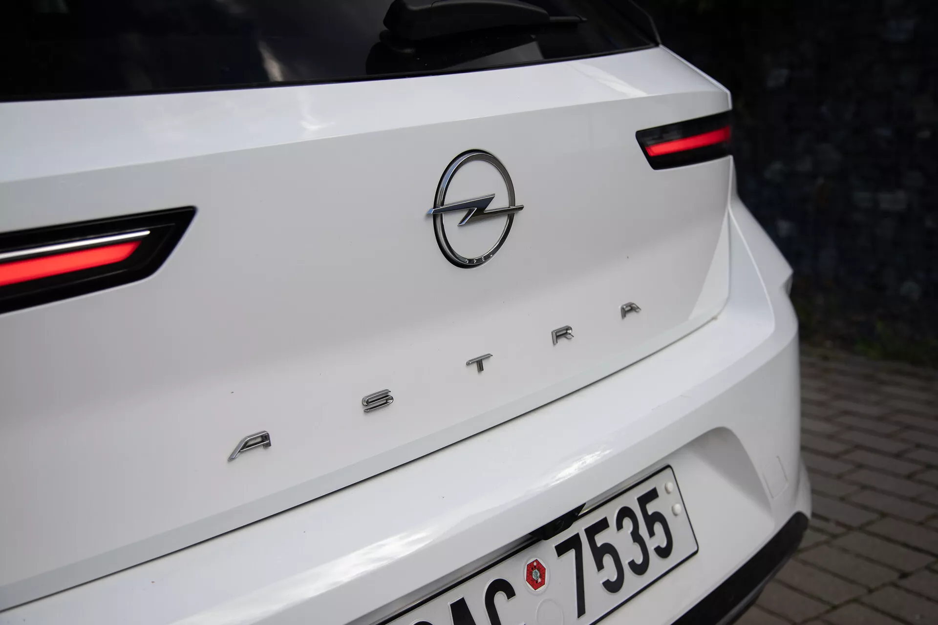 Vista ravvicinata della parte posteriore di un Opel Astra bianco del 2022, evidenziando i fanali posteriori LED, il logo Opel e il nome del modello 'ASTRA' sul coperchio del bagagliaio