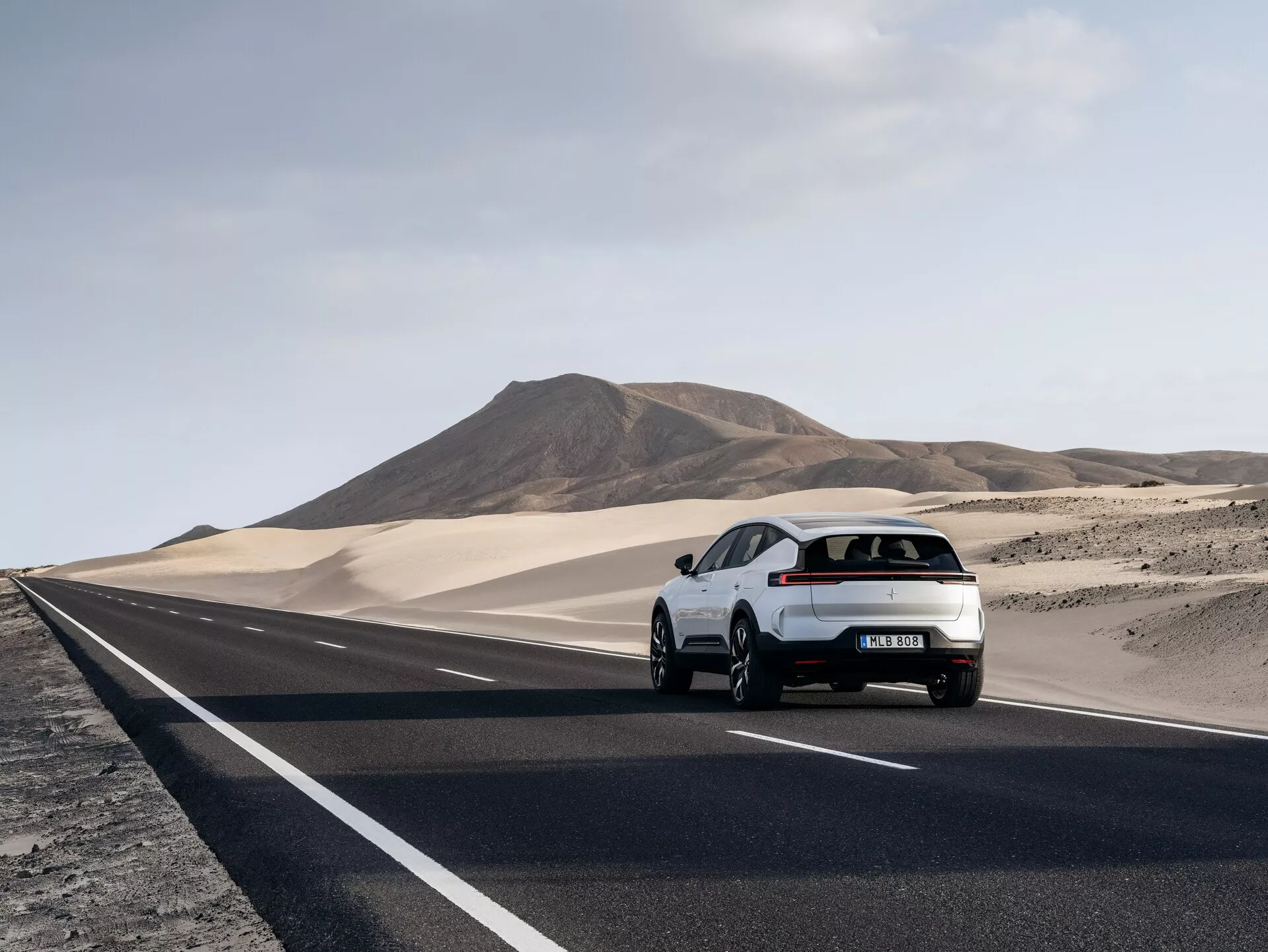 Polestar 3 hatchback 2023 in marcia su una strada desertica, mostra il suo lato sinistro posteriore e design aerodinamico con fanali posteriori LED