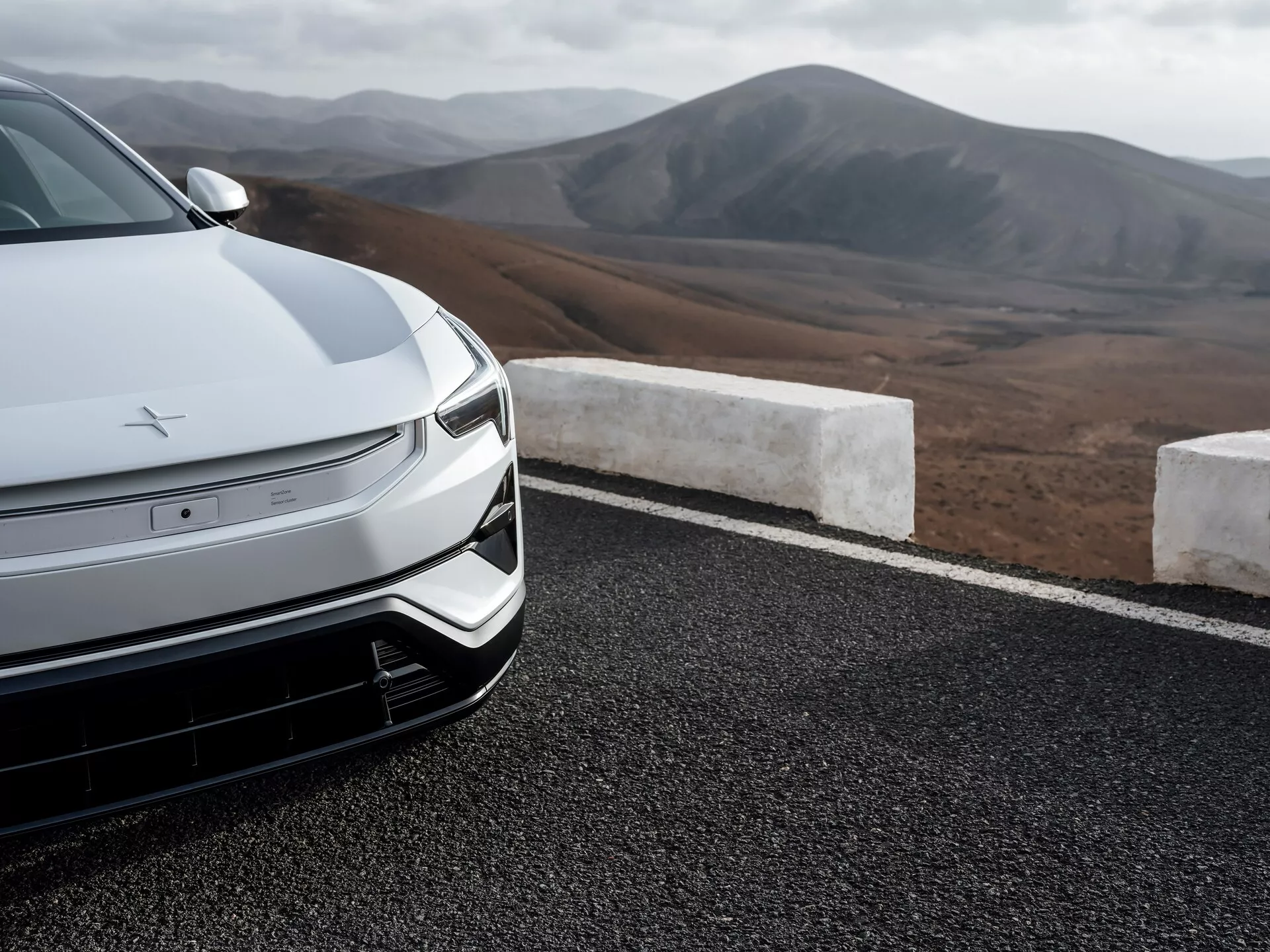 Vista ravvicinata della parte anteriore della berlina Polestar 3 2023 con aerodinamica avanzata, design del veicolo elettrico con fari LED e paesaggio montano sullo sfondo