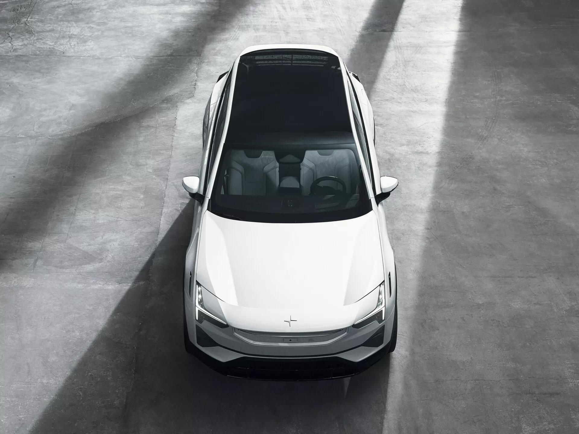Berlina Polestar 3 prima generazione 2023 mostrata da un angolo frontale alto in un ambiente showroom, evidenziando il suo design moderno, colore bianco e caratteristiche frontali tra cui il cofano, il tetto, il parabrezza, le porte anteriori, fari LED eleganti e griglia con badge oscurato, suggerendo possibili attributi di veicolo elettrico