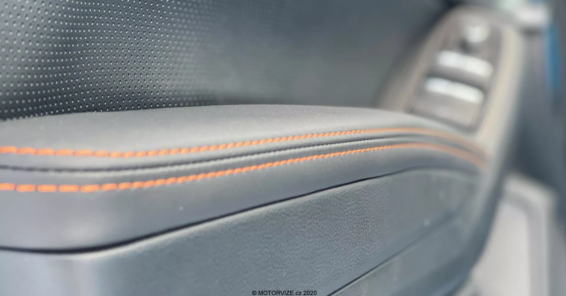 Primo piano del pannello porta interno della Subaru XV 2018, con cuciture arancioni precise su un materiale simile alla pelle con una finitura metallica e un pannello di controllo della finestra leggermente sfocato sullo sfondo, che mette in mostra l'artigianato premium e i dettagli di lusso.