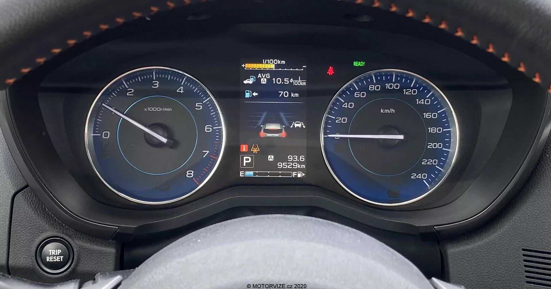 Vista ravvicinata del cruscotto della Subaru XV 1.6i Trend Lineartronic, che mostra un tachimetro analogico, un display multifunzione digitale e un tachimetro analogico. Il display digitale centrale mostra l'indicatore del carburante, lo stato del veicolo, la temperatura esterna di 10,5°C, un avviso di manutenzione, il cambio in parcheggio, un contachilometri con lettura di 95.249 km e l'ora alle 9:36. L'immagine cattura il cruscotto dal sedile del conducente, con dettagli aggiuntivi come una leva di controllo per luci e indicatori a sinistra e una vista parziale del volante con poggiapolsi e cuciture.