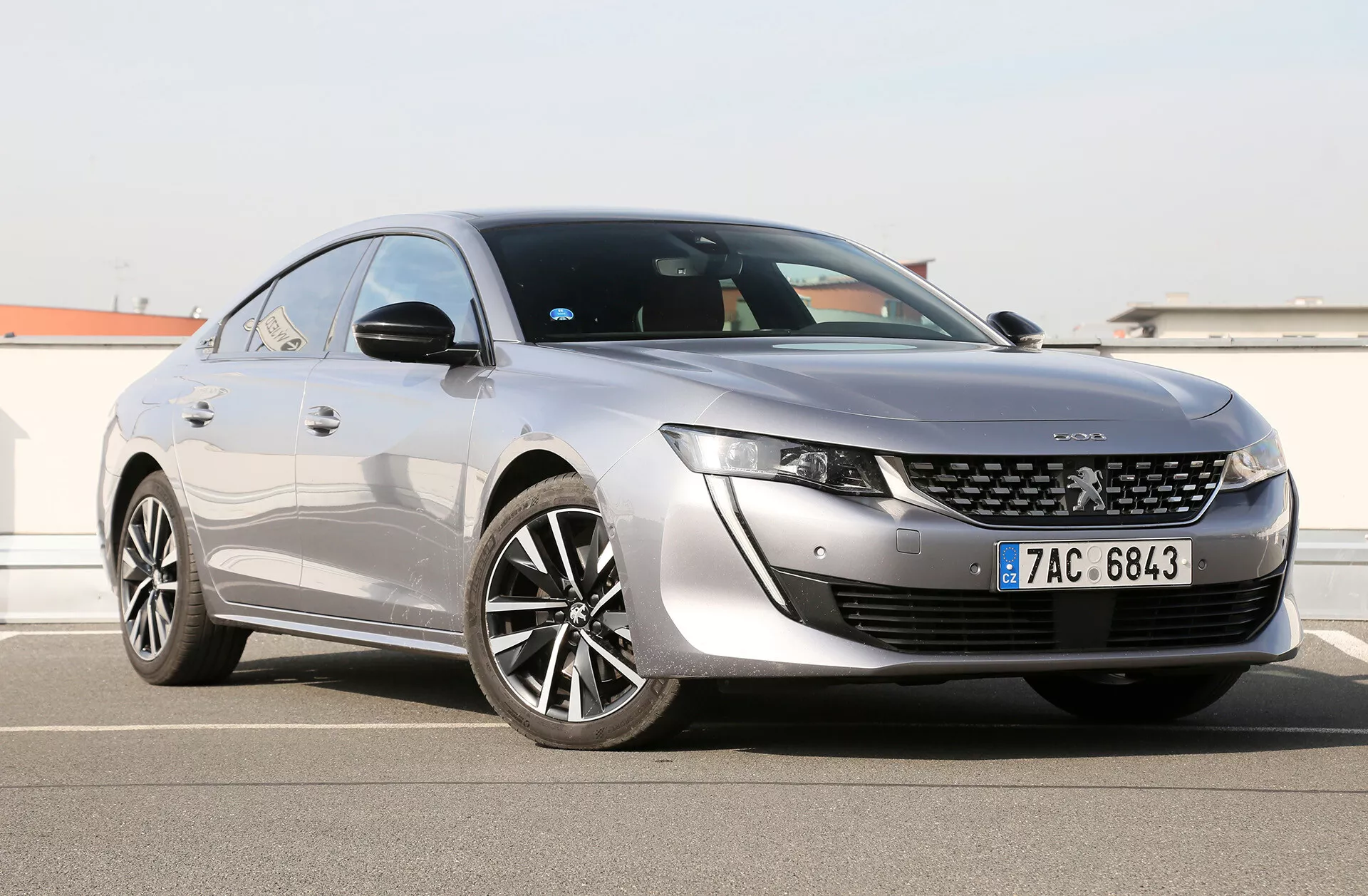Toyota Camry Limousine 2019 mostrata da un angolo frontale di tre quarti che evidenzia i suoi fari LED eleganti, griglia anteriore distintiva con badge centrale, cofano dal design aerodinamico e profilo laterale con grandi ruote in lega a più razze, vernice lucida e linea del tetto coupé-like