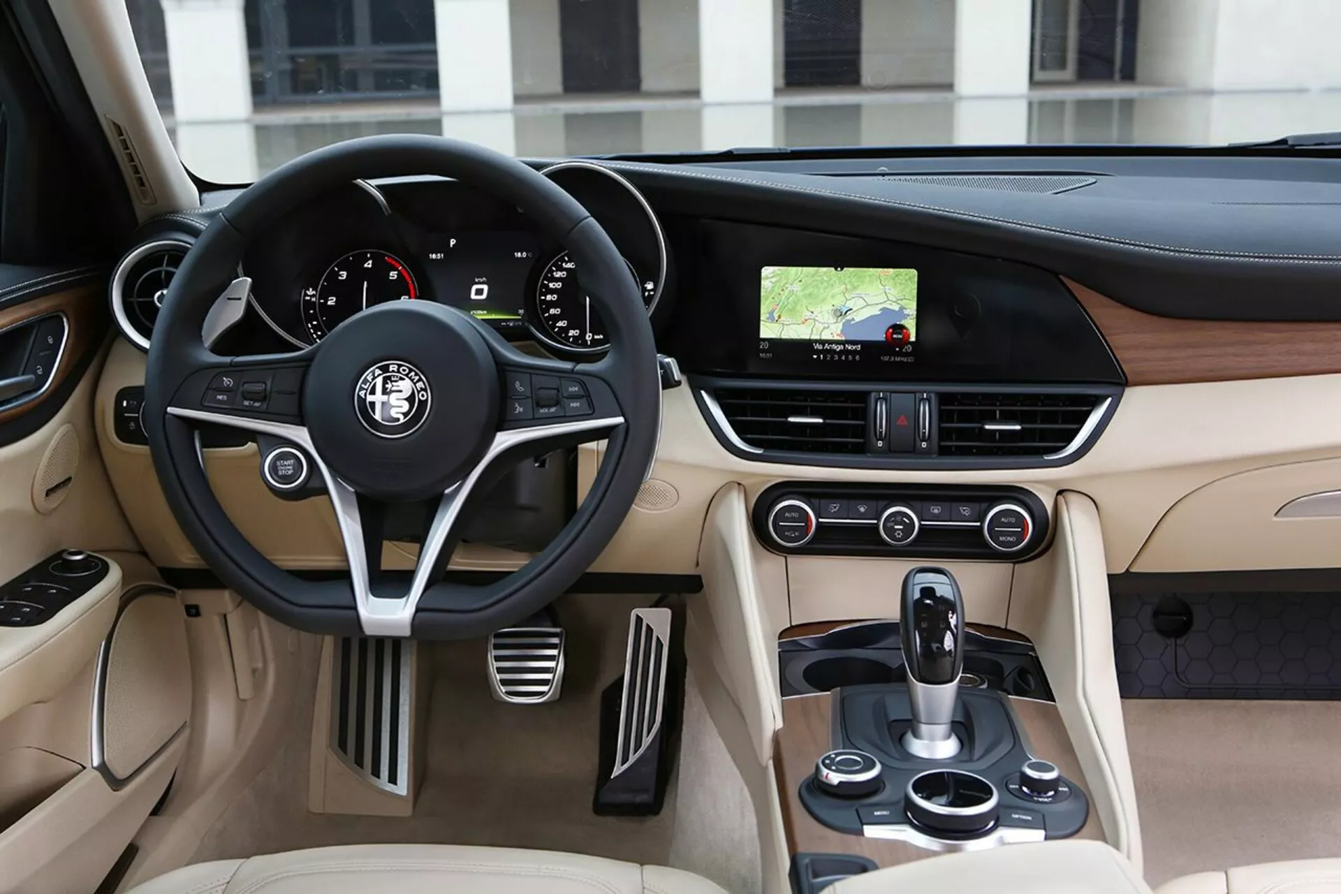 Vista interna della Alfa Romeo Giulia 2016 che mostra il lato guidatore con volante in pelle, cruscotto e console centrale