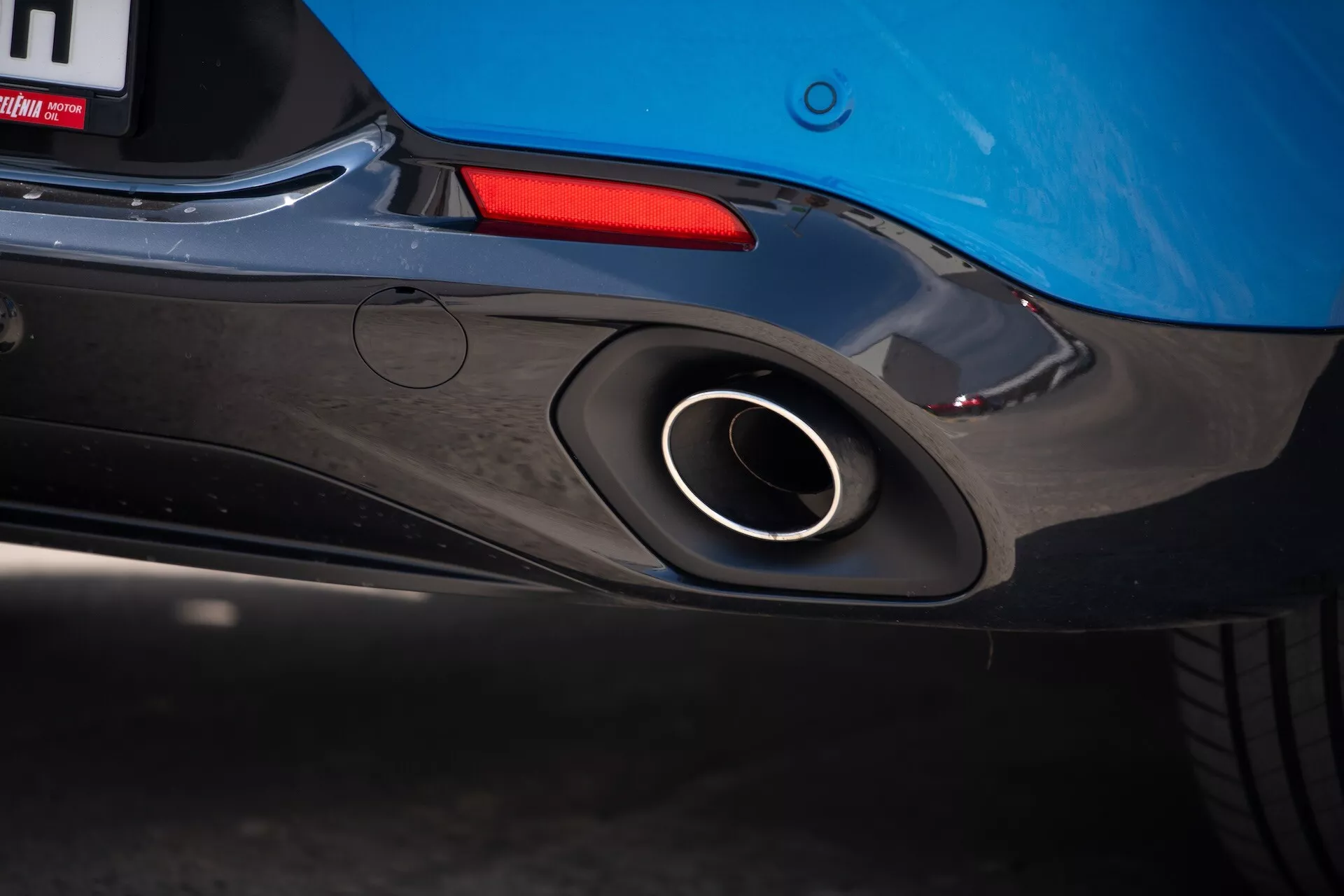 Vista ravvicinata della sezione posteriore dell'Alfa Romeo Tonale 2022 con in evidenza il tubo di scarico sportivo, design aerodinamico del paraurti posteriore e colore blu della carrozzeria con uno scorcio della luce posteriore