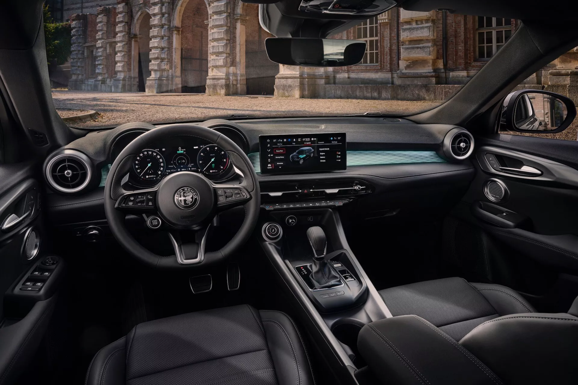 Vista interna dell'Alfa Romeo Tonale 2022 dal sedile posteriore passeggero con cockpit, volante con comandi, cruscotto digitale, schermo infotainment orizzontale, console centrale con leva del cambio e sedili in pelle di lusso