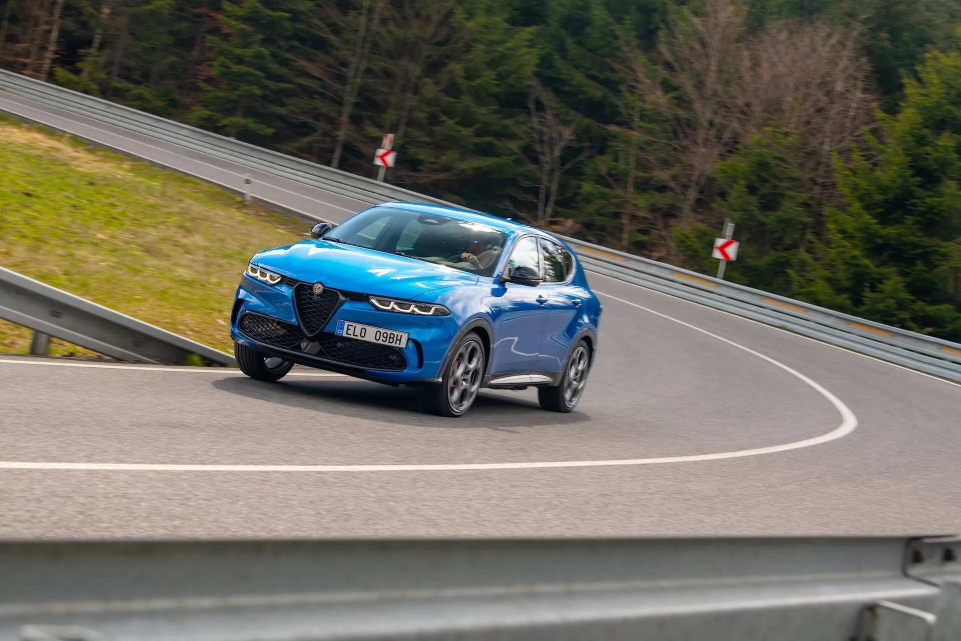 SUV Alfa Romeo Tonale 2022 in movimento con design dinamico e fari LED, grandi ruote in lega e caratteristiche sportive, catturato da un angolo laterale basso che enfatizza la sua velocità e finitura blu metallico lucido