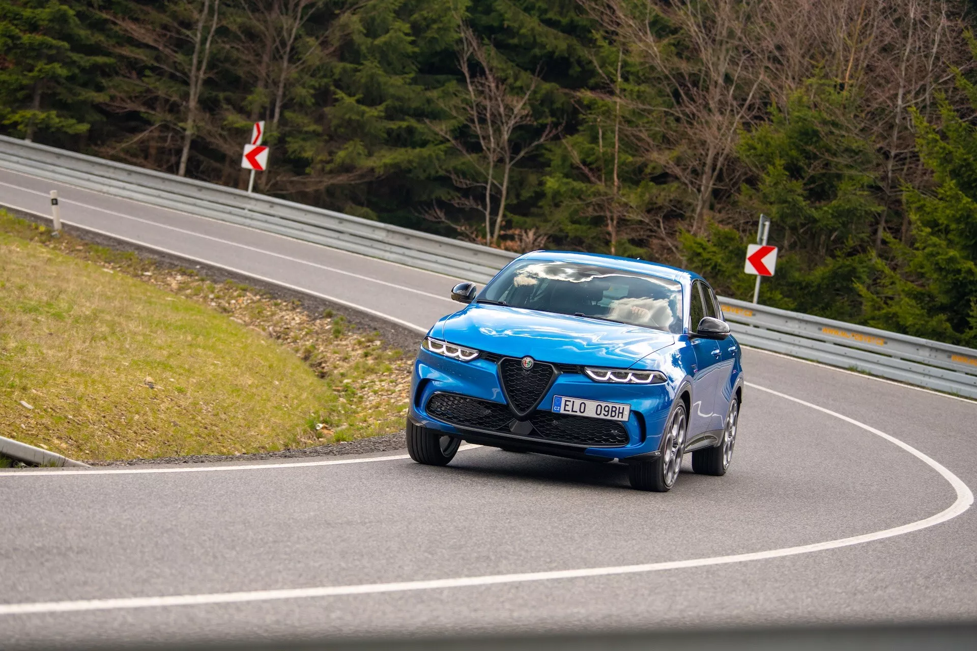 Guida dinamica della Alfa Romeo Tonale 2022 su strada curva che mostra vista frontale, fari LED, griglia distintiva e cerchi performance