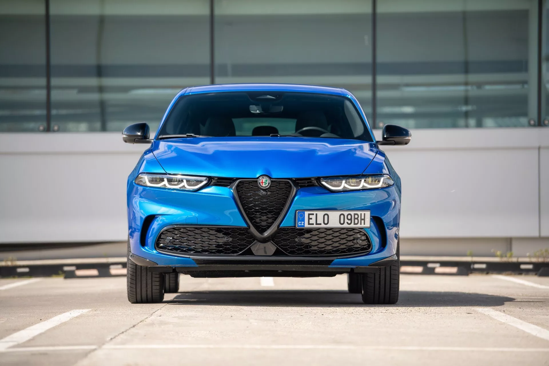 Alfa Romeo Tonale 2022 blu, vista frontale in parcheggio con griglia ed emblema, fari LED e caratteristiche di design aerodinamico
