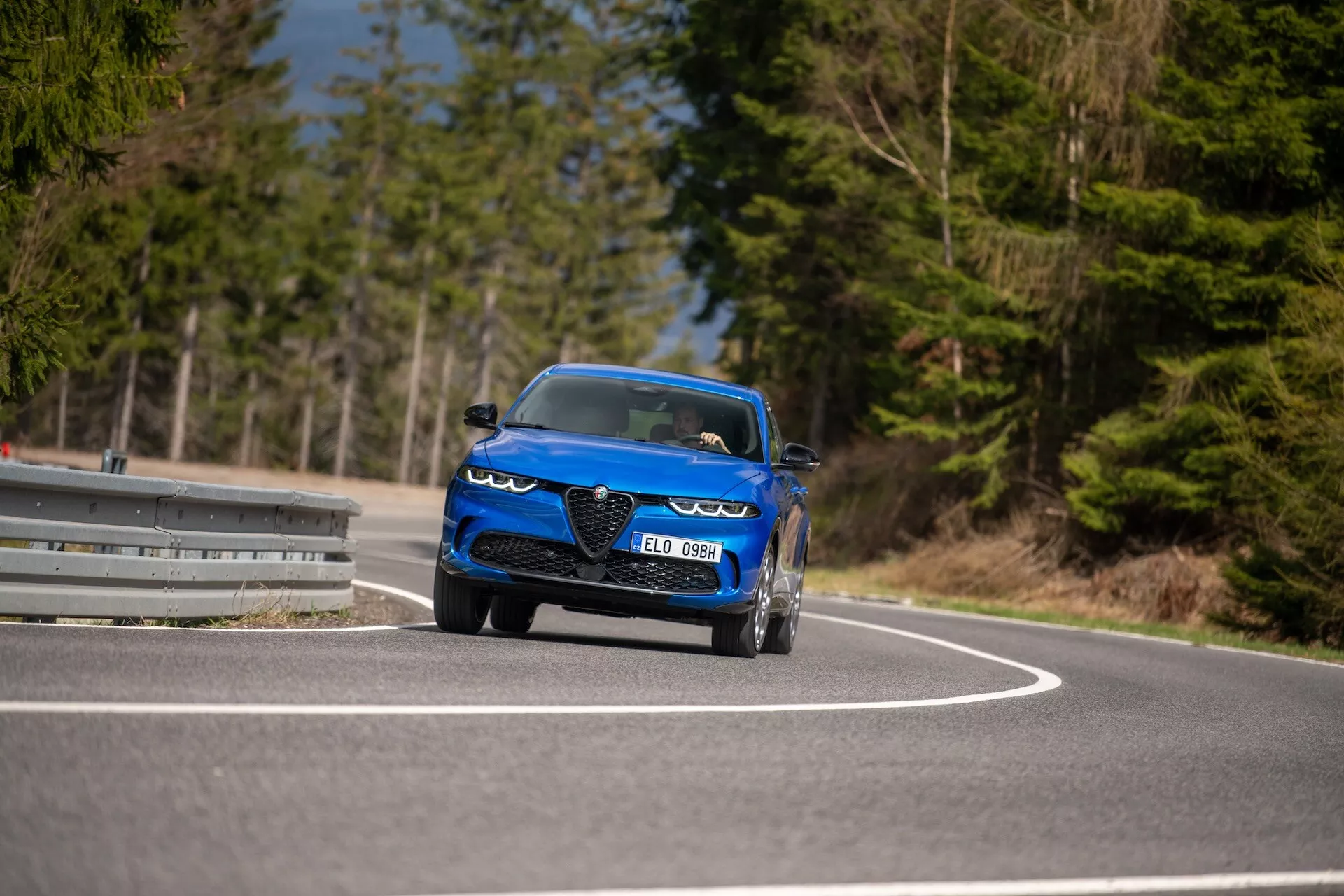 Alfa-Romeo Tonale 2022 in movimento su una strada curva, mette in risalto il suo design dinamico, fari LED, prese d'aria, stile convertibile sportivo e caratteristiche di lusso da una prospettiva frontale a tre quarti con angolo basso