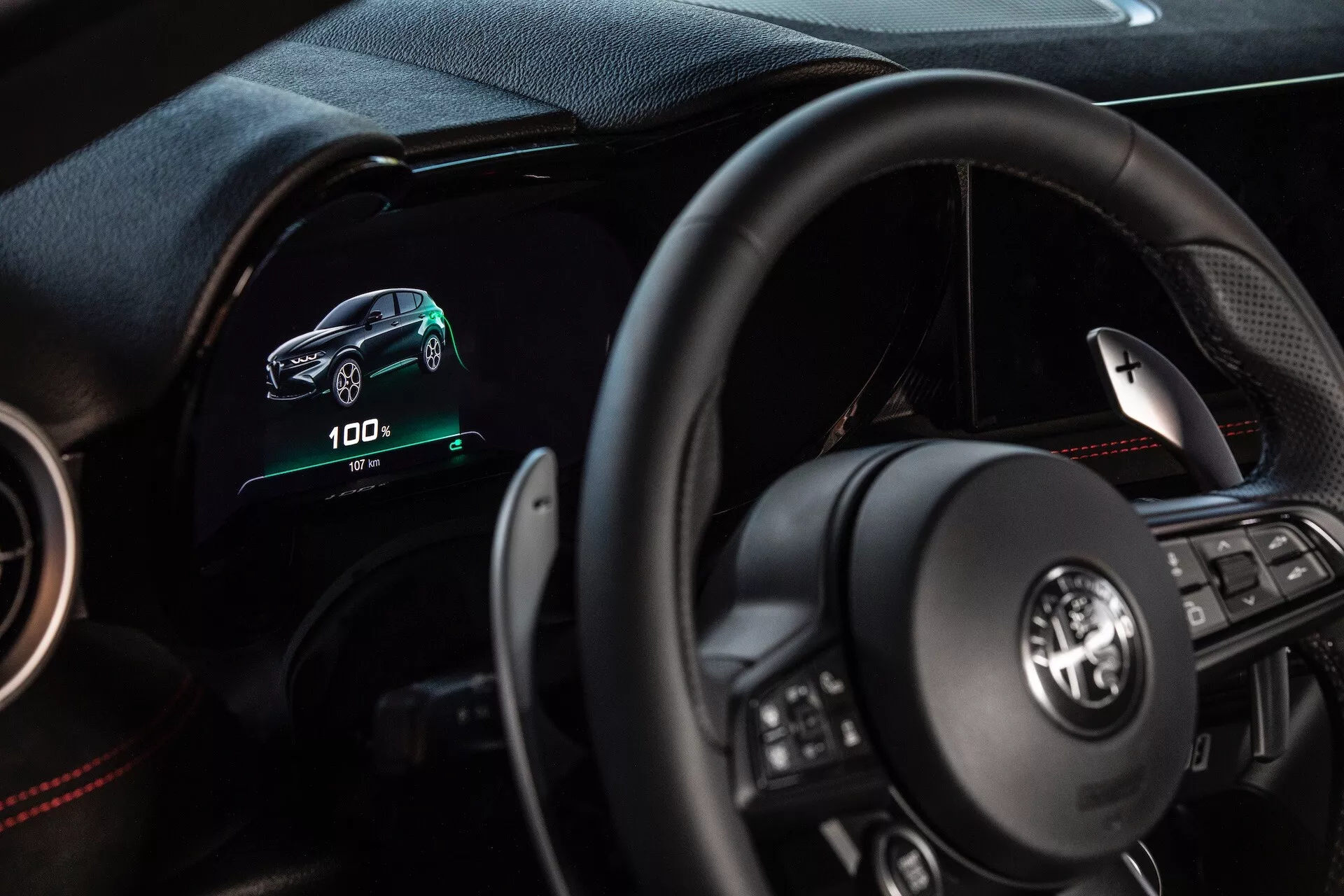 Interno dell'Alfa Romeo Tonale 2022 che mostra la prospettiva del guidatore con cruscotto digitale, volante multifunzione e indicatori per veicoli elettrici