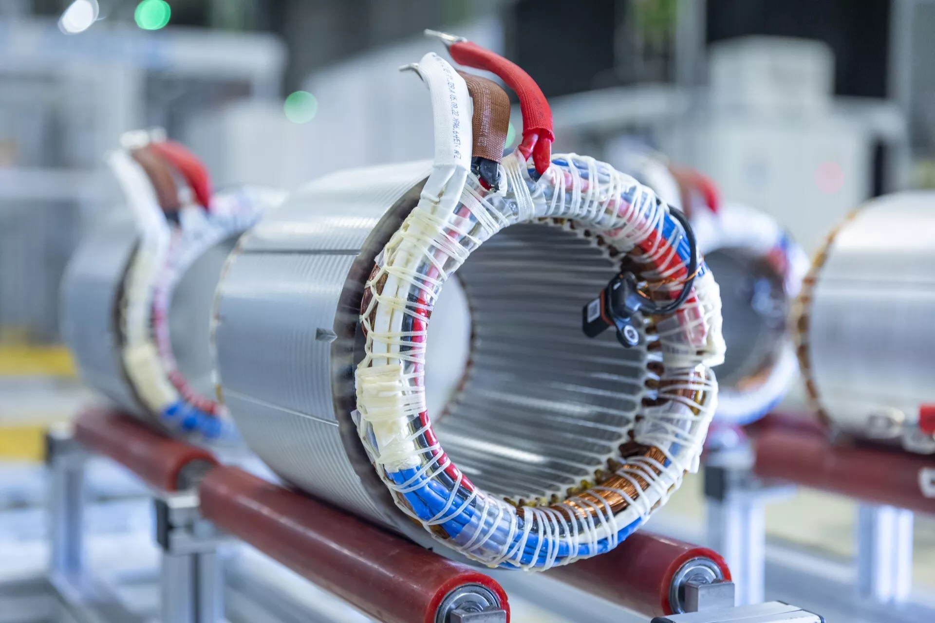 Foto ad alta risoluzione di uno statore di motore elettrico montato su supporto rosso, che mostra avvolgimenti di filo avvolti attorno a nuclei metallici laminati tipici nella macchinaria elettrica per generare campi magnetici