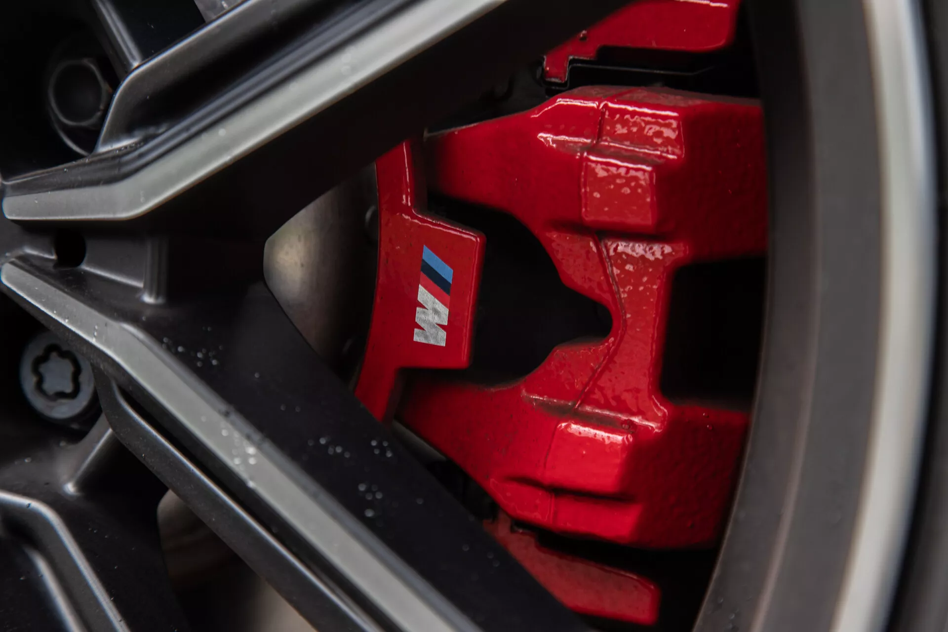 Vista ravvicinata della pinza del freno rossa vivace e del rotore sulla BMW Serie 2 Coupé 2022, con design multipistone, marchio 'M', cerchio in lega leggera scura a più razze e pneumatico a basso profilo ad alte prestazioni. Il rotore ventilato migliora il raffreddamento in condizioni di frenata intensa, catturato in stile macrofotografico per enfatizzare gli aspetti delle prestazioni.