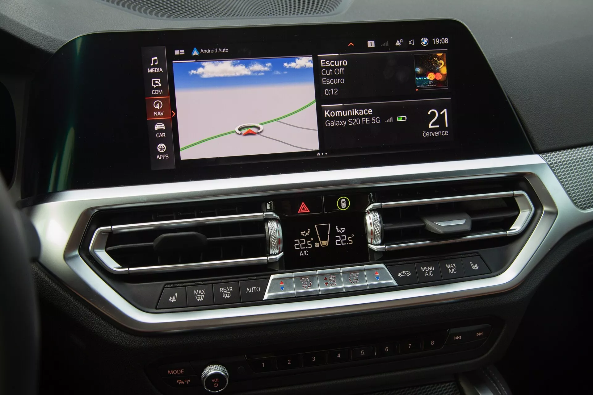La consolle centrale della BMW Serie 2 Coupé 2022 mette in evidenza il moderno sistema di infotainment e i controlli del clima della vettura. L'immagine mostra un ampio schermo touchscreen a colori che visualizza una mappa di navigazione, icone di integrazione Bluetooth o smartphone e un orologio. Sotto lo schermo ci sono due bocchette centrali dell'aria con lamelle regolabili e un elegante pannello con pulsanti touch e un display LCD per il controllo del clima a doppia zona. Il design degli interni, con accenti in metallo spazzolato e texture simili alla fibra di carbonio, riflette un ambiente lussuoso e tecnologicamente avanzato.
