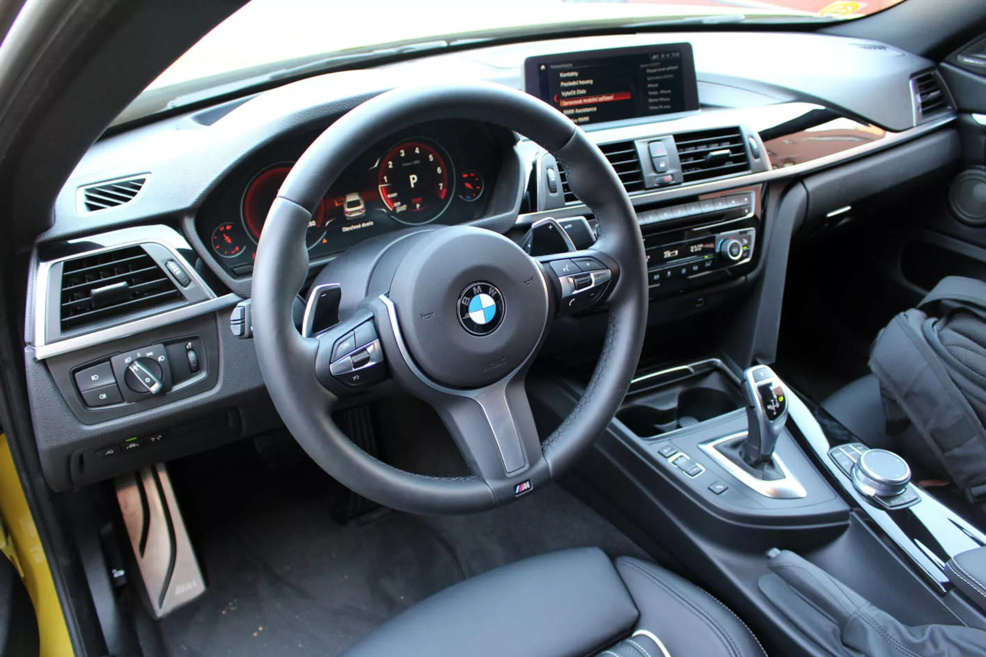 Vista interna di una coupé BMW Serie 4 del 2013 dalla prospettiva del conducente mostrando il volante, il cruscotto, la console centrale con controlli multimediali e per il clima, la leva del cambio e finiture di lusso