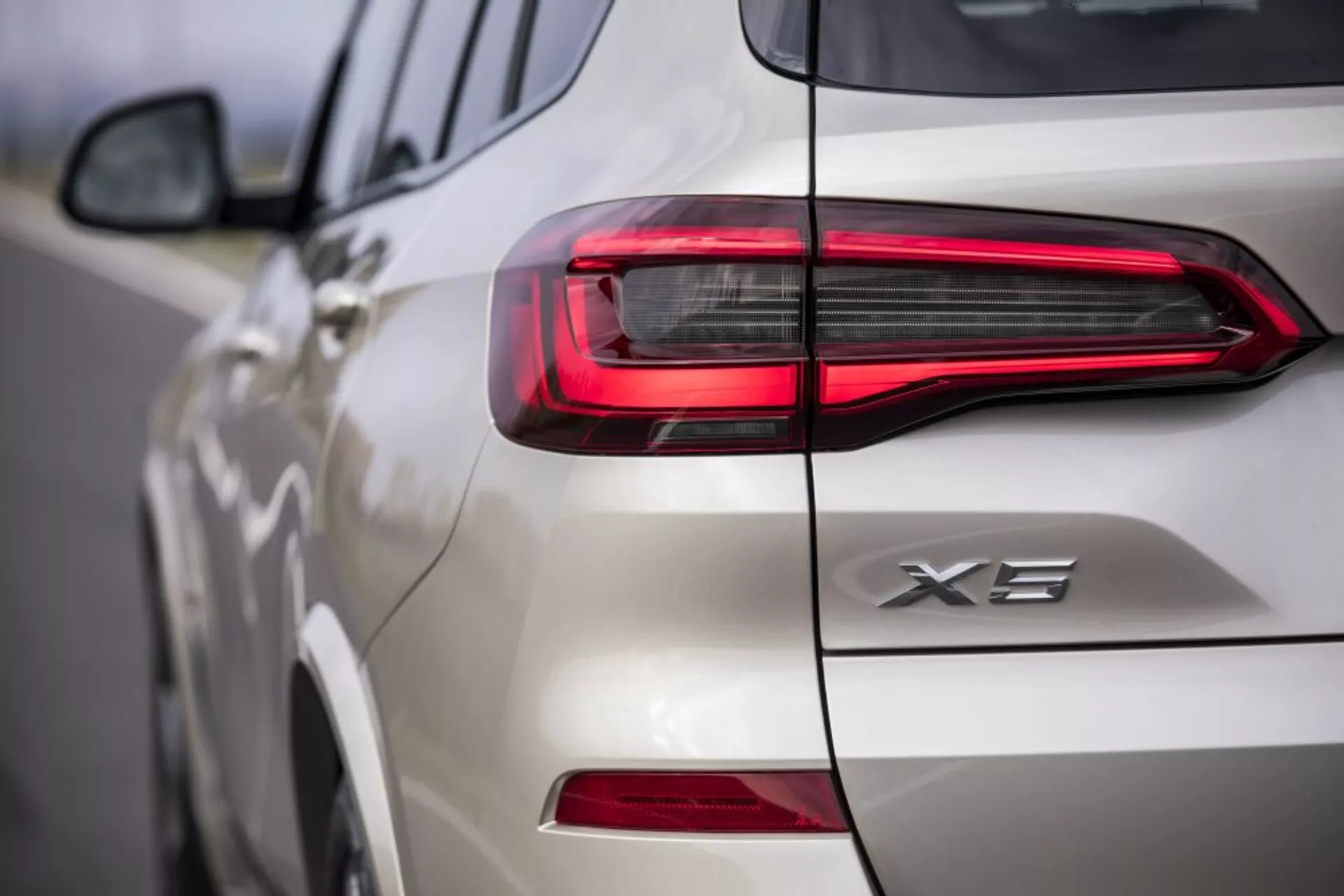 Vista ravvicinata della parte posteriore di una BMW X3 2018 bianca, mettendo in mostra il design del faro posteriore LED e il distintivo X3, concentrandosi sulla moderna firma luminosa orizzontale e su dettagli intricati sul portellone e sul lato.