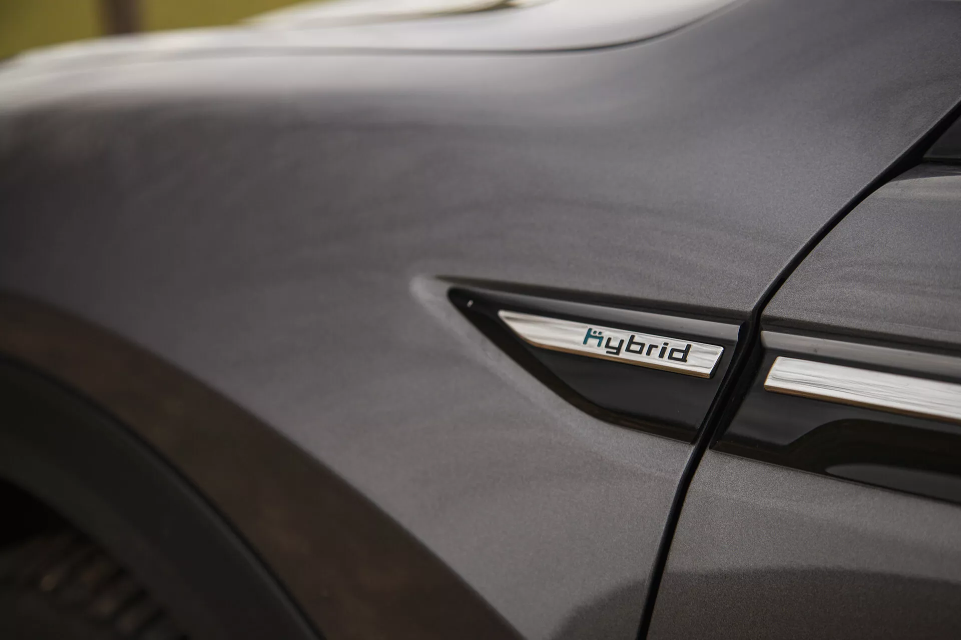 Dettaglio ravvicinato del Citroen C5-X 2022 con l'insignia Ibrido sul profilo laterale inferiore vicino al passaruota posteriore, esaltando la tecnologia ibrida e l'estetica del design in condizioni di illuminazione morbida