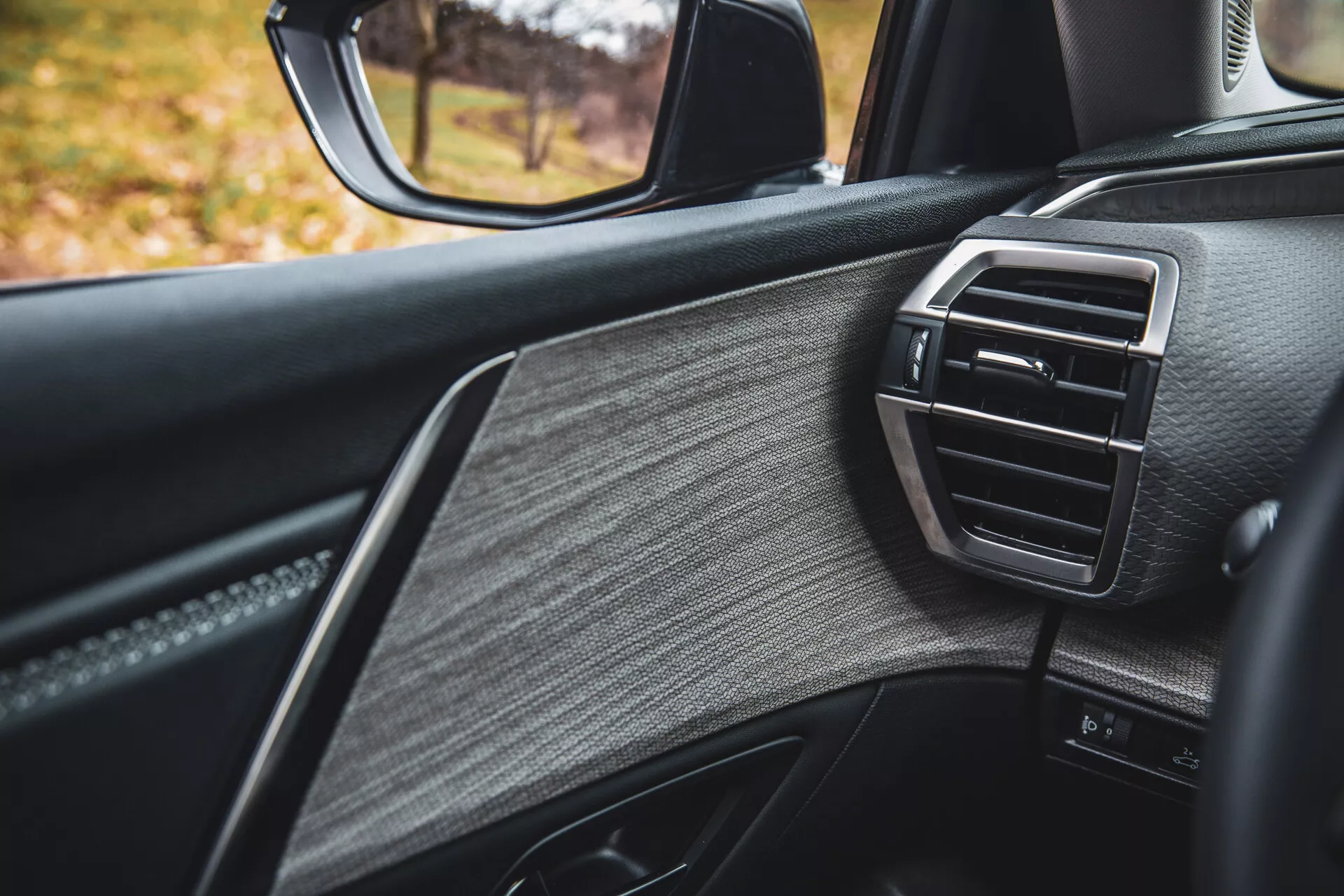 Vista dettagliata della porta lato passeggero della Citroen C5-X 2022, che mostra un design di lusso con pelle testurizzata, rifiniture lucide e bocchetta dell'aria del controllo clima