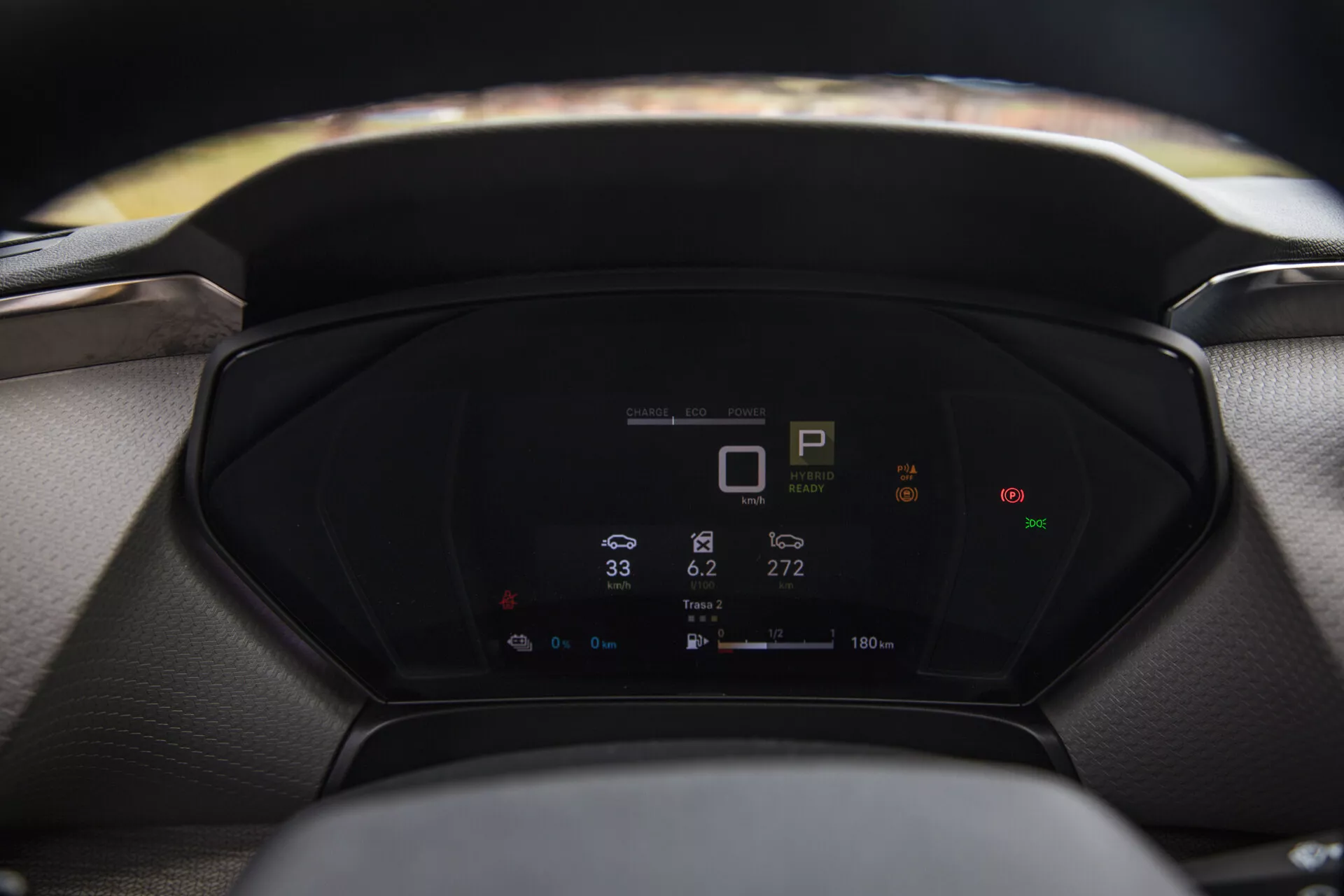 Vista ravvicinata del cruscotto digitale di una Citroen C5-X 2022 che mostra le metriche del veicolo, inclusi indicatore di marcia, velocimetro e consumo energetico, con volante e parabrezza sfocati in primo piano e sfondo rispettivamente.