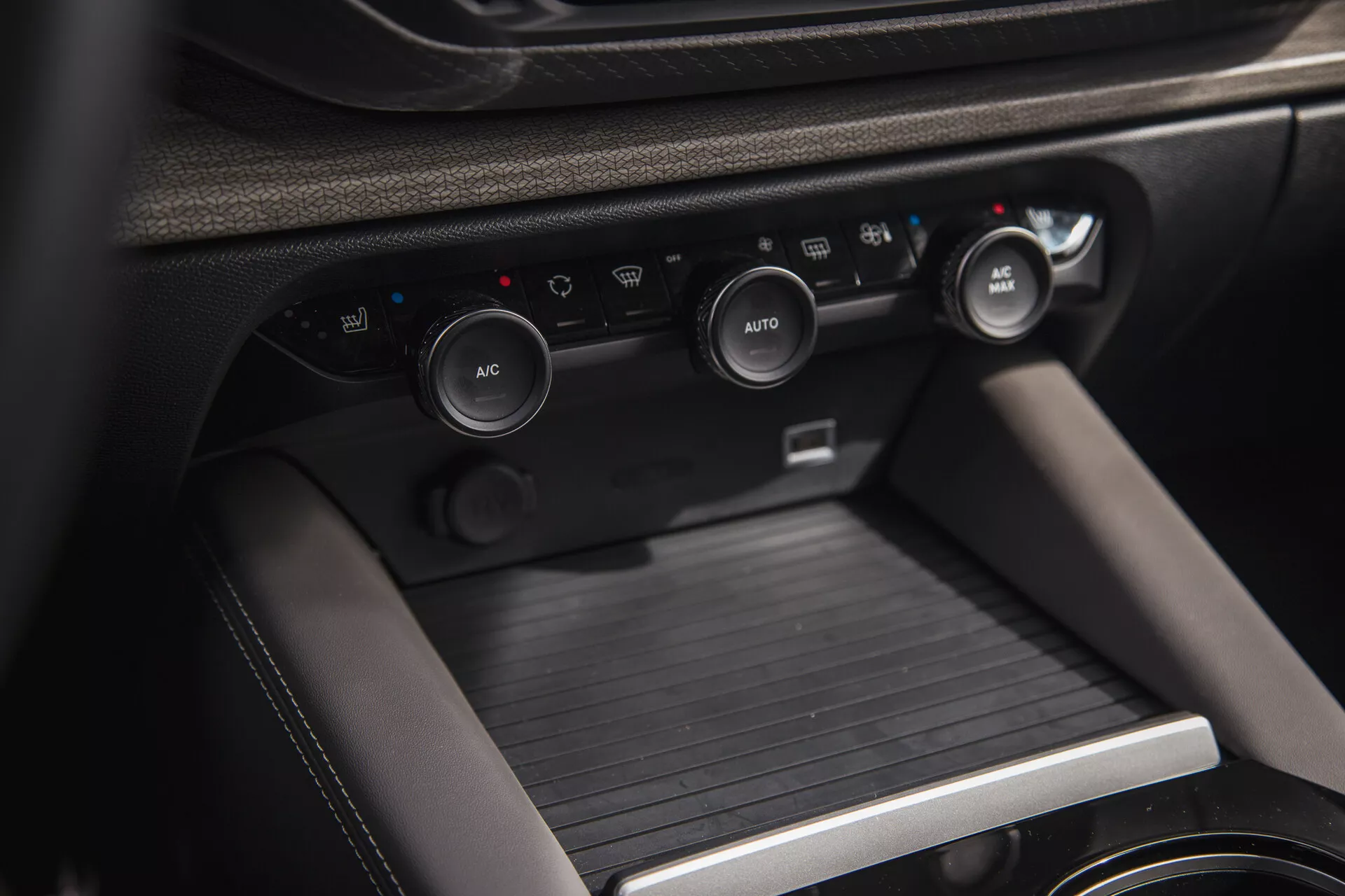 Vista ravvicinata dell'interno del Citroen C5-X 2022, presentando la console centrale con i pomelli di controllo del clima e la console del cambio, evidenziando il sistema climatico avanzato del veicolo, soluzioni di stoccaggio e materiali di alta qualità.