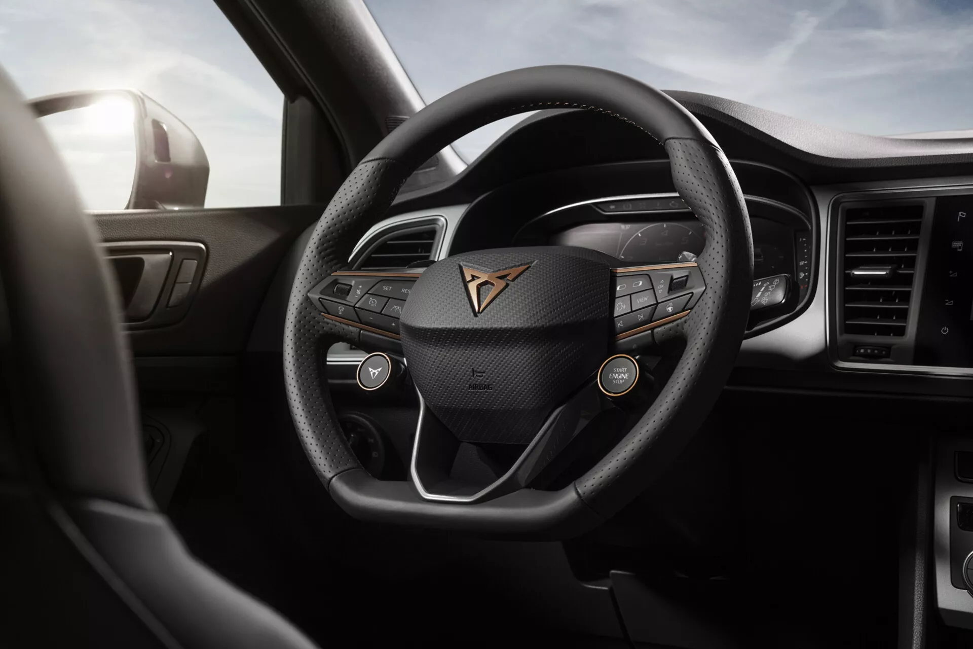 Interno della Cupra Ateca 2020 con volante moderno a tre razze in pelle con emblema del marchio, quadro strumenti digitale e display centrale dell'infotainment tra materiali di alta qualità e design sofisticato, dalla prospettiva del conducente.