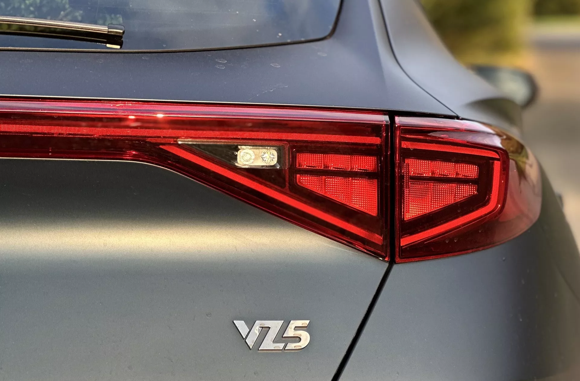 Vista posteriore di una Cupra Formentor VZ5 2020 con focus sul design del fanale posteriore LED, emblema e carrozzeria metallica di alta qualità, catturata da un angolo di tre quarti con bassa profondità di campo