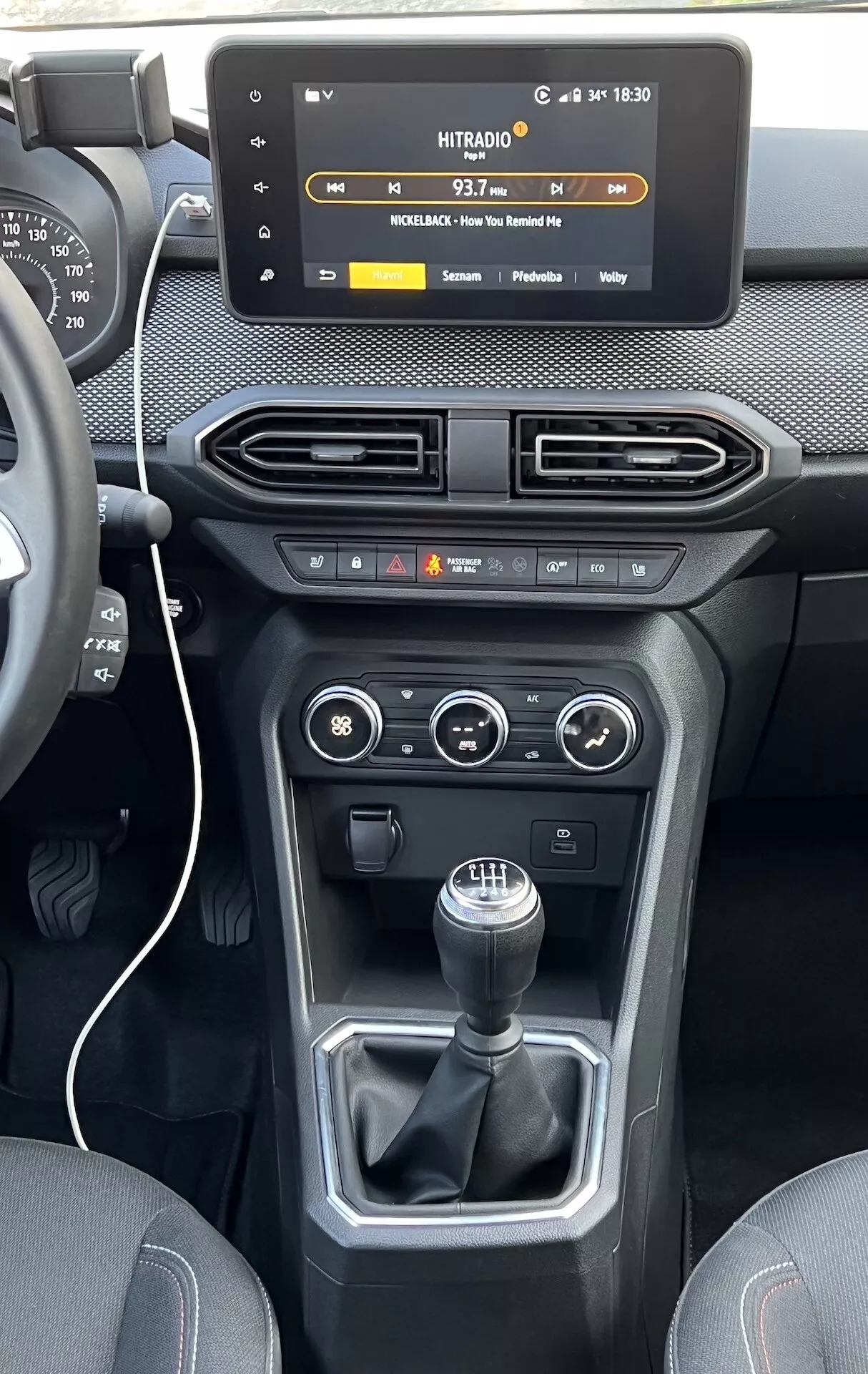 Vista interna della Dacia Jogger 2022 focalizzata sulla console centrale e cruscotto, con schermo touch infotainment stile floating, bocchette aria, comandi clima e veicolo, e leva cambio manuale