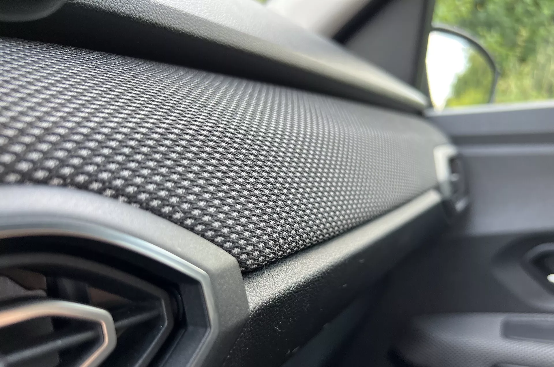 Vista ravvicinata del cruscotto lato passeggero della Dacia Jogger 2022 con motivo in fibra di carbonio e bocchetta d'aria, che enfatizza il design moderno e gli interni di lusso