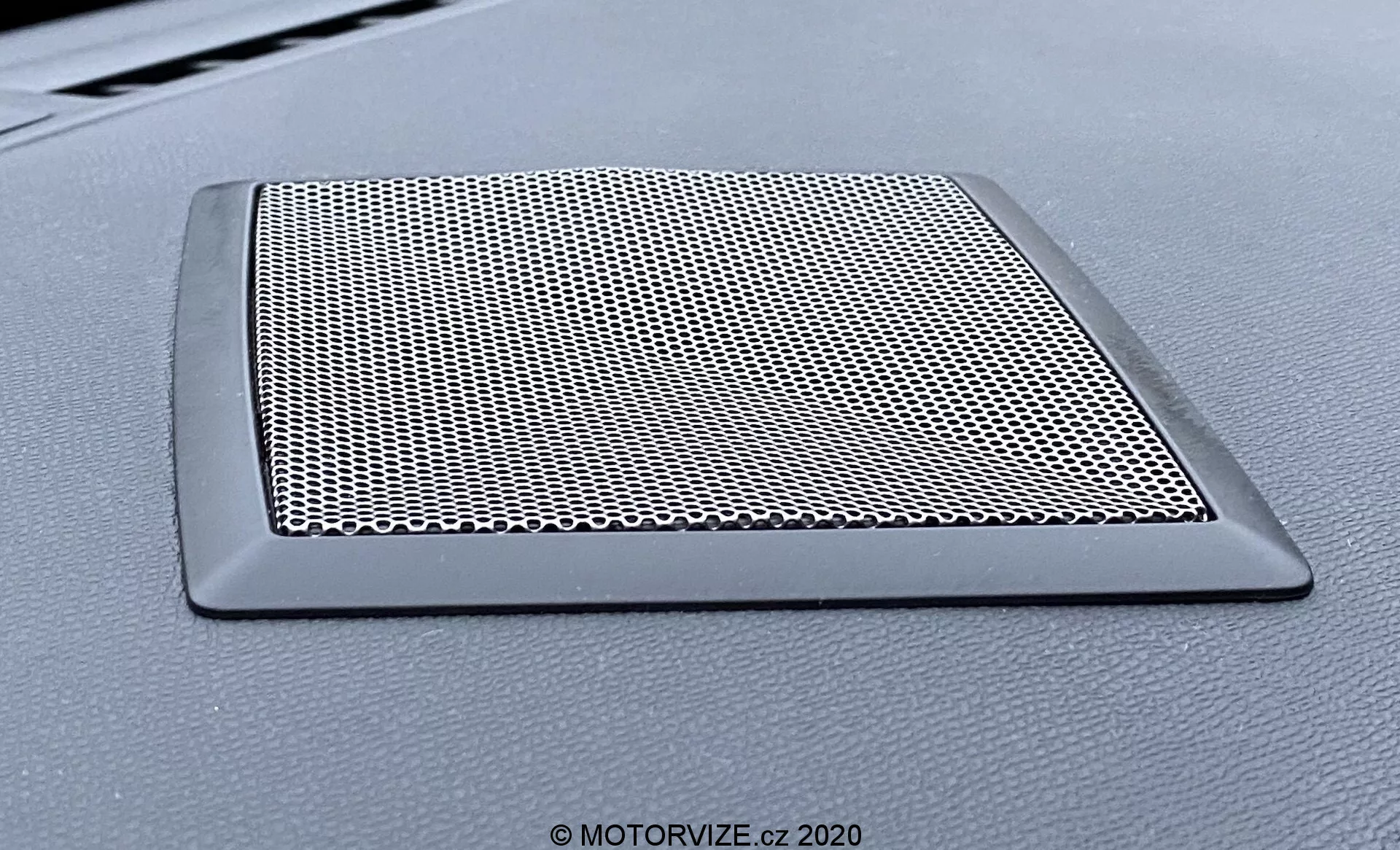 Vista ravvicinata della griglia dell'altoparlante sul cruscotto del veicolo DS Automobiles DS-3 Crossback modello 2019. La griglia trapezoidale presenta una rete fittamente tessuta per la protezione dell'altoparlante e un bordo elegante e non riflettente che si fonde con il cruscotto.