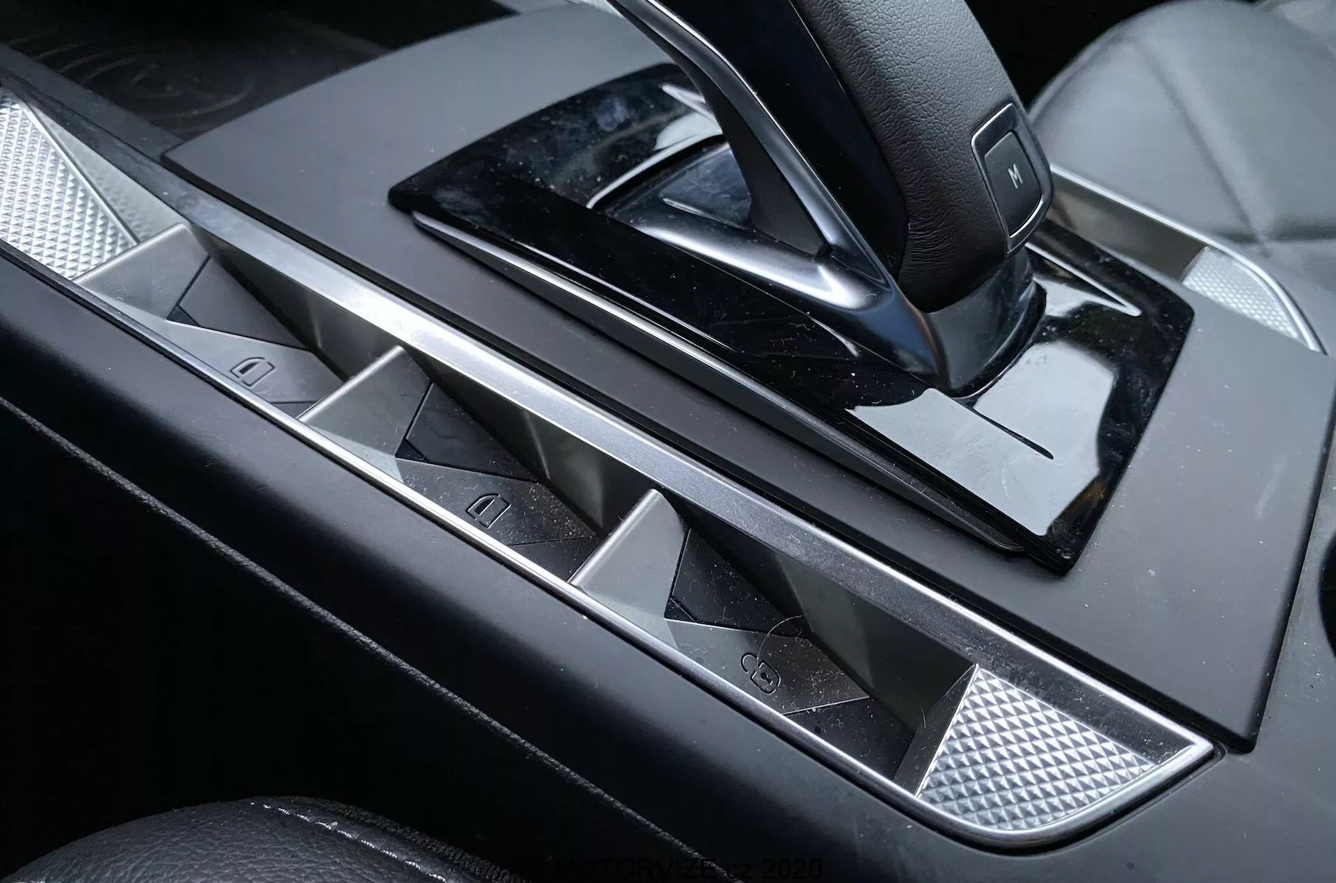 Vista ravvicinata del pannello di controllo della portiera del conducente del lussuoso DS Automobiles DS-3 Crossback 2019, con maniglia della portiera in metallo lucido, pulsanti dei finestrini elettrici con accenti cromati, joystick per le regolazioni degli specchietti laterali, finitura nera lucida e inserto a griglia metallica per un tocco di raffinatezza.