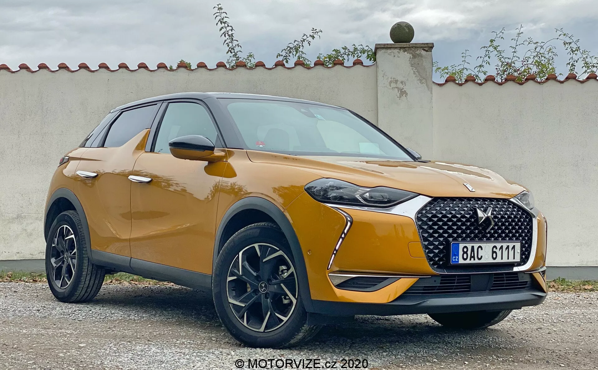 Vista anteriore a tre quarti della DS Automobiles DS 3 Crossback 2019. L'immagine mostra il moderno SUV crossover con la sua distintiva griglia, i fari LED eleganti e gli alloggiamenti per i fari fendinebbia. La finitura della vernice metallica, il contorno liscio del cofano e i cerchi in lega enfatizzano un design sportivo e di alta classe. Gli specchietti laterali aerodinamici con indicatori di direzione integrati e le modanature in plastica intorno agli archi delle ruote contribuiscono all’estetica robusta del veicolo.