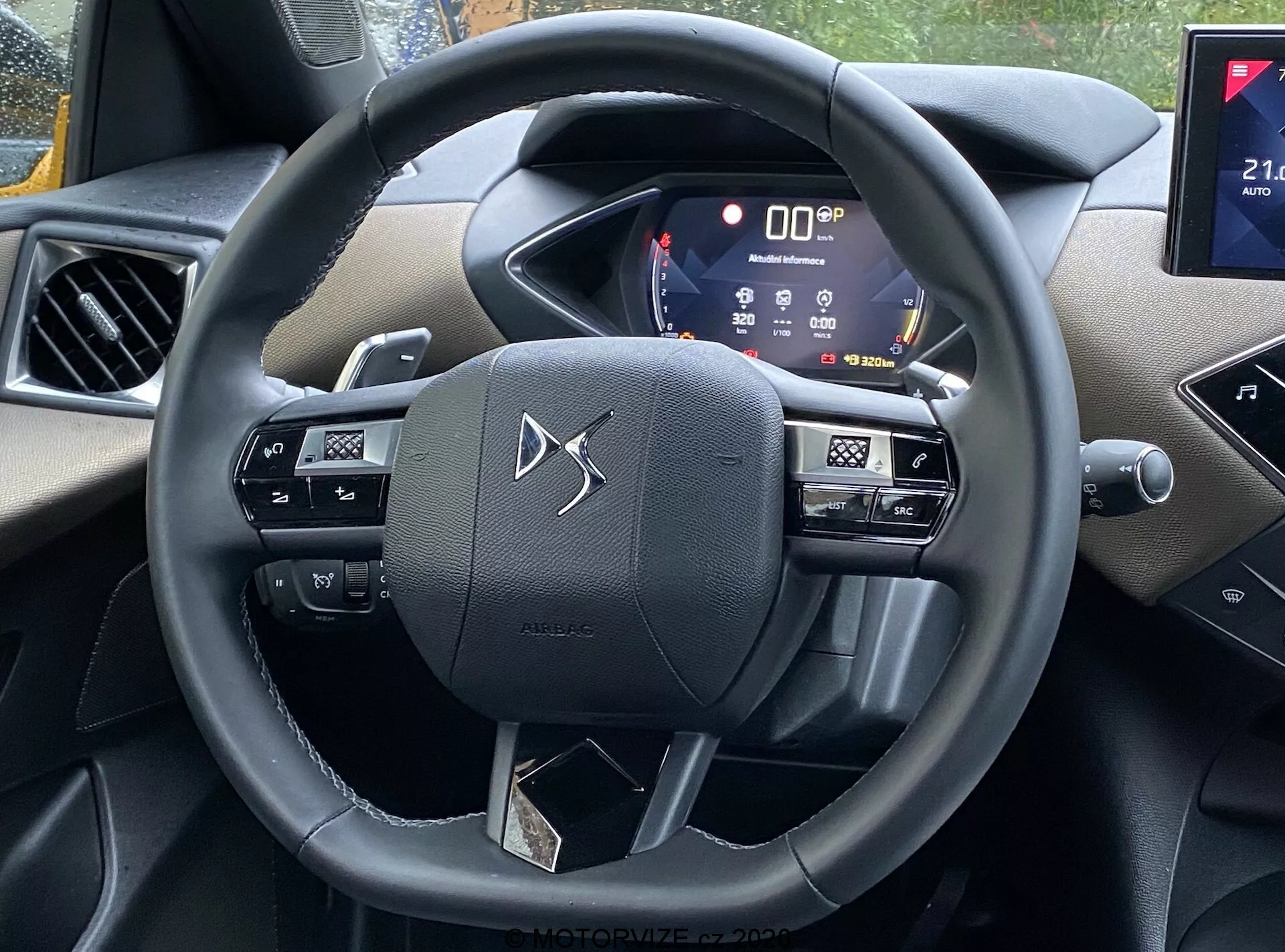 Vista interna della DS Automobiles DS-3 2019 (DS-3 Crossback) dalla prospettiva del sedile del conducente, con il volante con pulsanti per i controlli multimediali, comandi vocali e probabilmente impostazioni del cruise control, un quadro strumenti digitale attivo che visualizza varie informazioni del veicolo e una parte del sistema di infotainment, probabilmente con connettività per smartphone e funzionalità di navigazione. Gli interni includono una combinazione di plastiche soft-touch e accenti cromati, mostrando tecnologia moderna e fascino estetico.