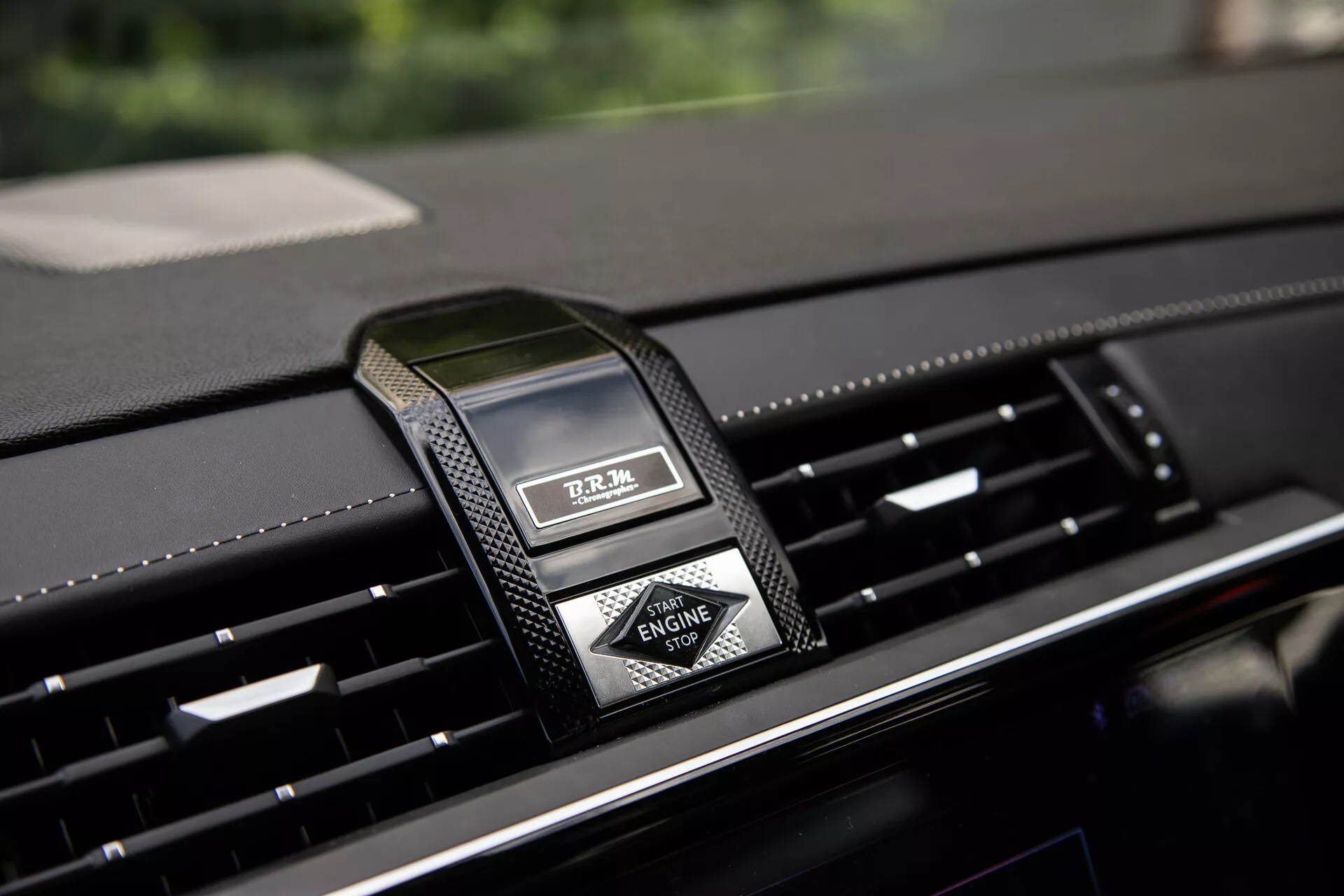 Primo piano della plancia centrale della DS Automobiles DS-7 2022 con orologio analogico di lusso e bocchette d'aria, evidenziando materiali premium e design moderno