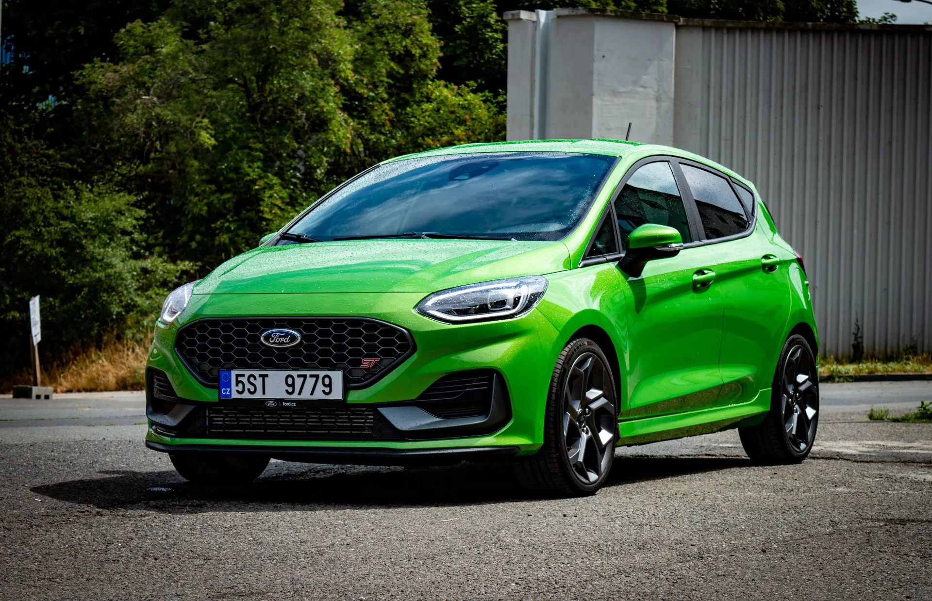 Hatchback Ford Fiesta 2022 verde vibrante in vista frontale a tre quarti con griglia anteriore con emblema, paraurti sportivo con luci di nebbia, fari angolati affilati, contorni aerodinamici, grandi ruote in lega nera e sistema di illuminazione moderno