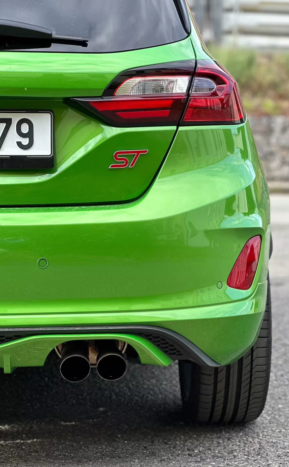 Vista ravvicinata del retro di Ford Fiesta ST 2022 in finitura verde brillante metalizzato, che mostra fari posteriori LED, doppio scarico cromato e diffusore posteriore aerodinamico