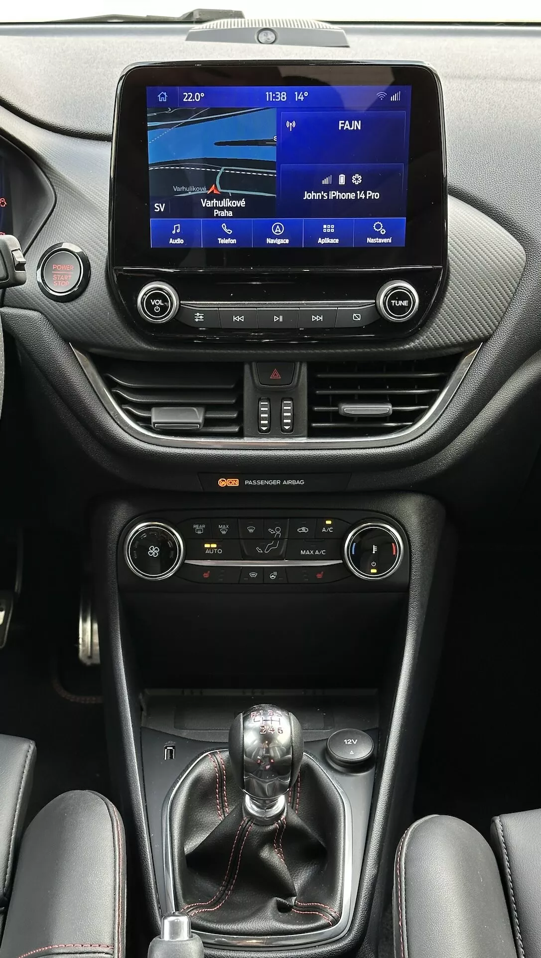 Interni della Ford Fiesta 2022 con sistema di infotainment touchscreen, controlli climatici duali, trasmissione manuale e accenti di lusso in pelle visti dal lato passeggero