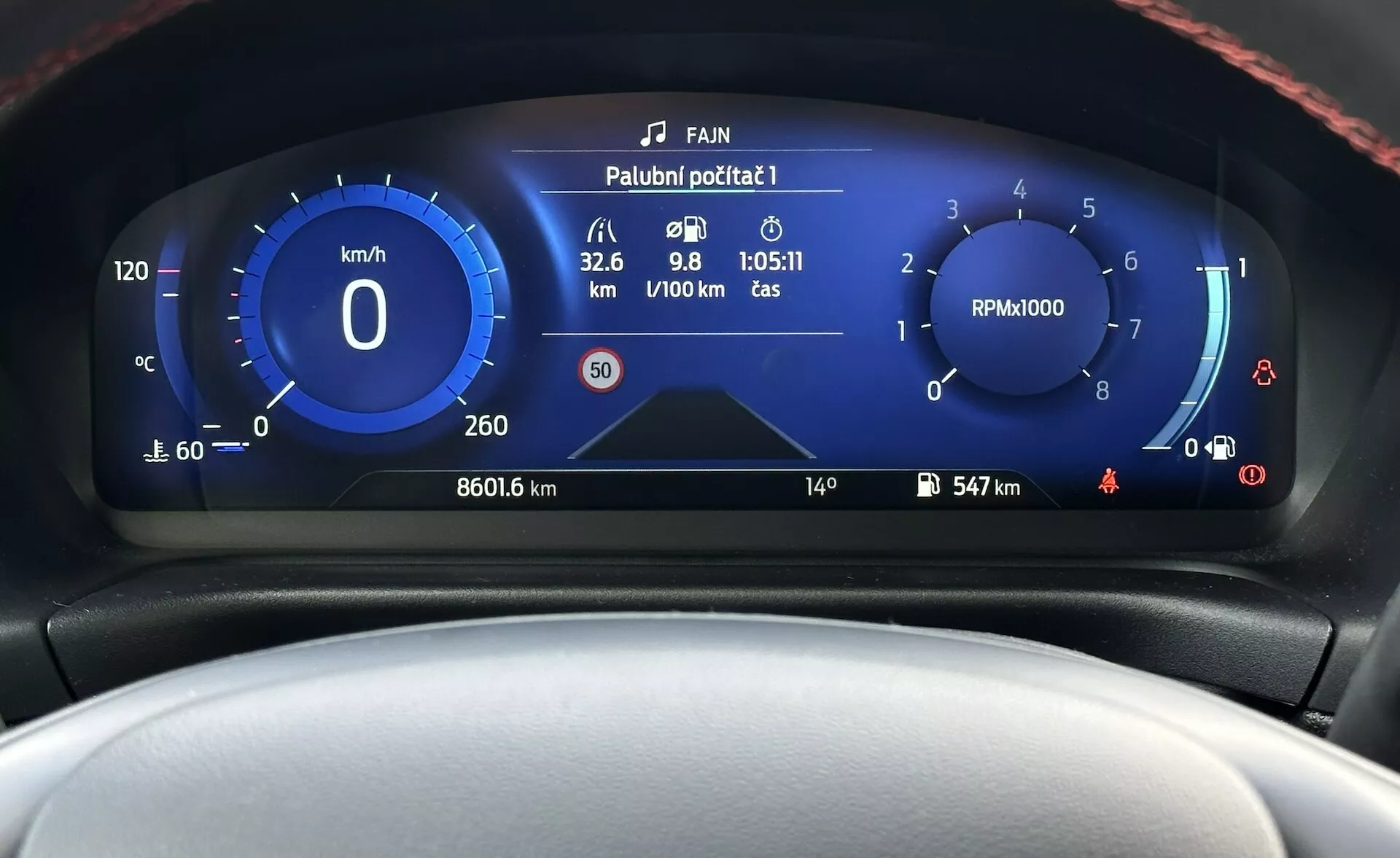 Cruscotto digitale della Ford Fiesta 2022 che mostra una vista frontale ravvicinata con tachimetro, contagiri, indicatore di efficienza del carburante e vari indicatori dello stato del veicolo in un design moderno con schema di colori blu e bianco.