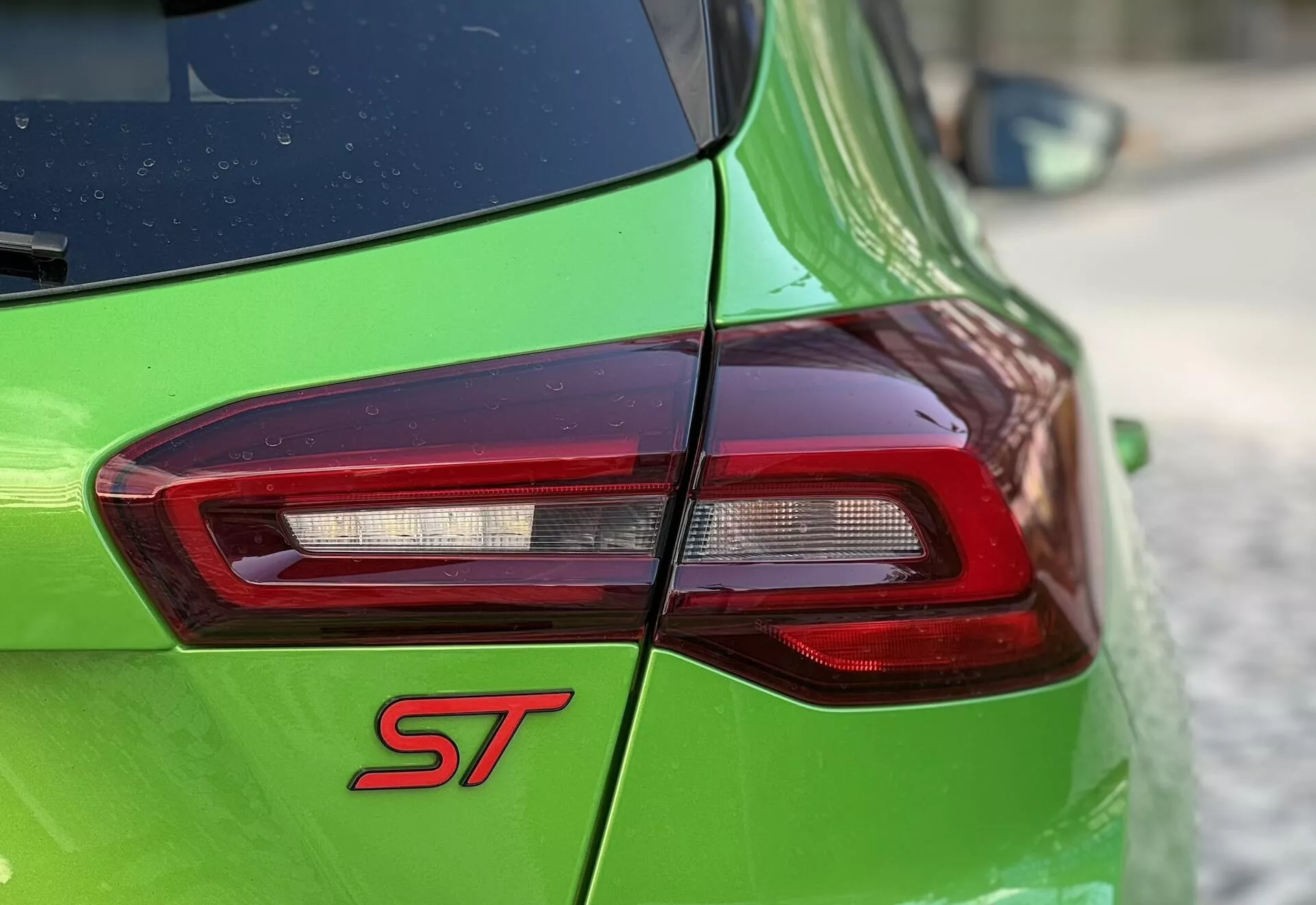 Primo piano della parte posteriore della Ford Focus ST 2022 con fanale posteriore LED e vernice verde che evidenzia il badge sportivo ST e la tecnologia di illuminazione avanzata