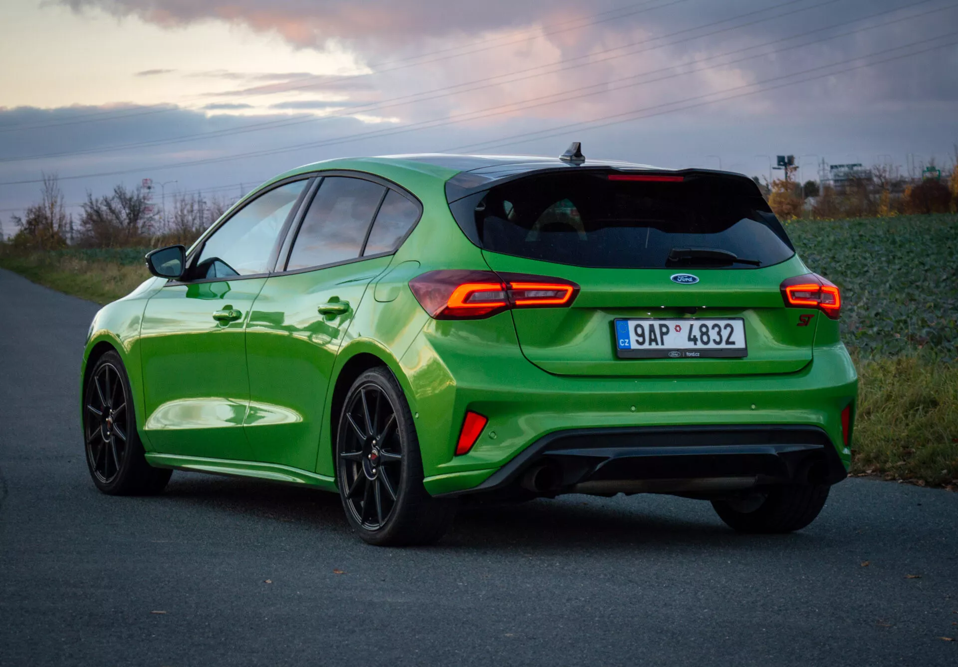 Ford Focus ST 2022 in verde vibrante con design sportivo, vista posteriore tre quarti che mostra fanali posteriori, ruote e doppio scarico