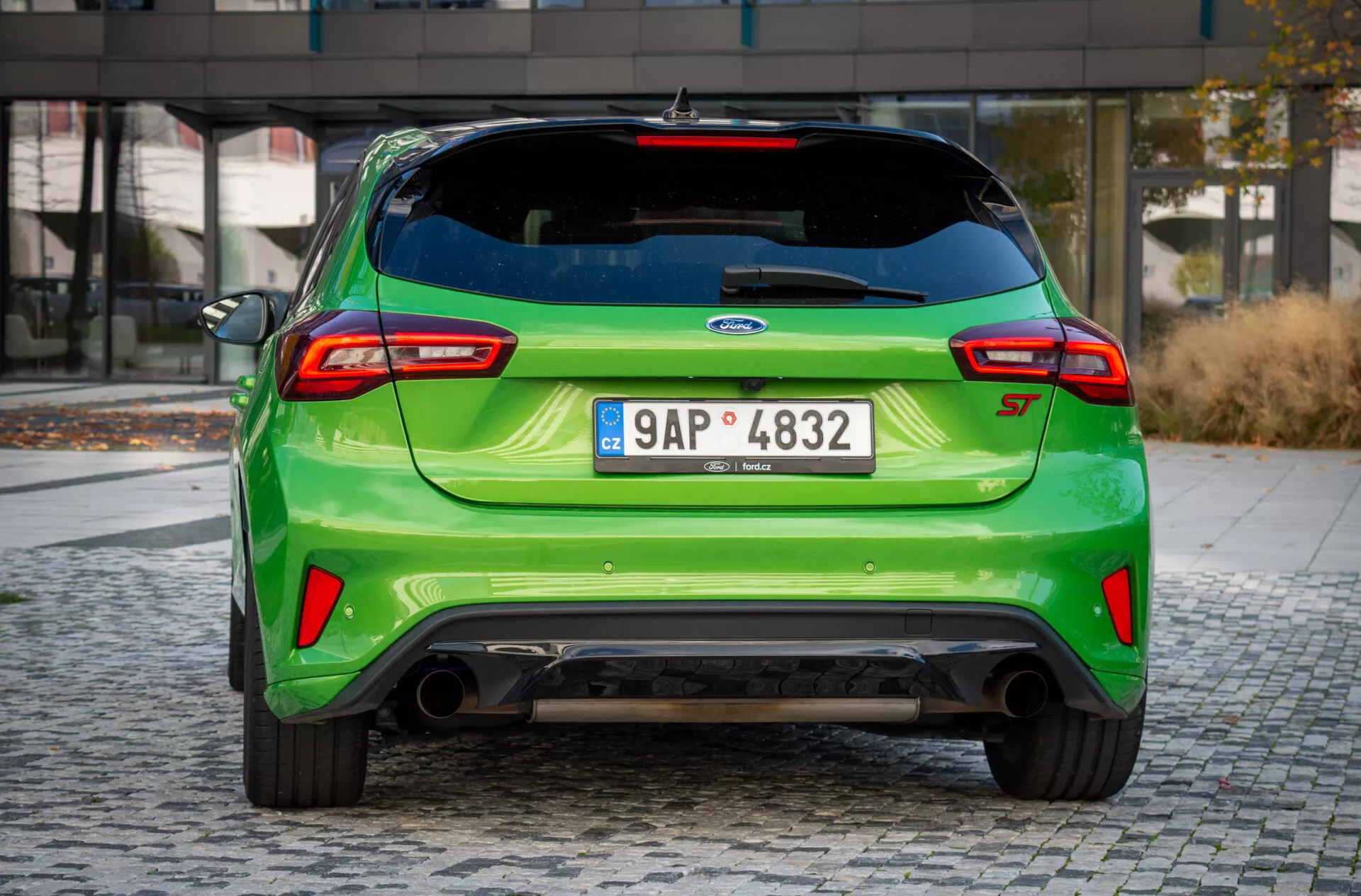Vista angolare posteriore della Ford Focus ST 2022, mettendo in evidenza il colore verde brillante, lo scarico sportivo, lo spoiler aerodinamico e i fanali posteriori moderni