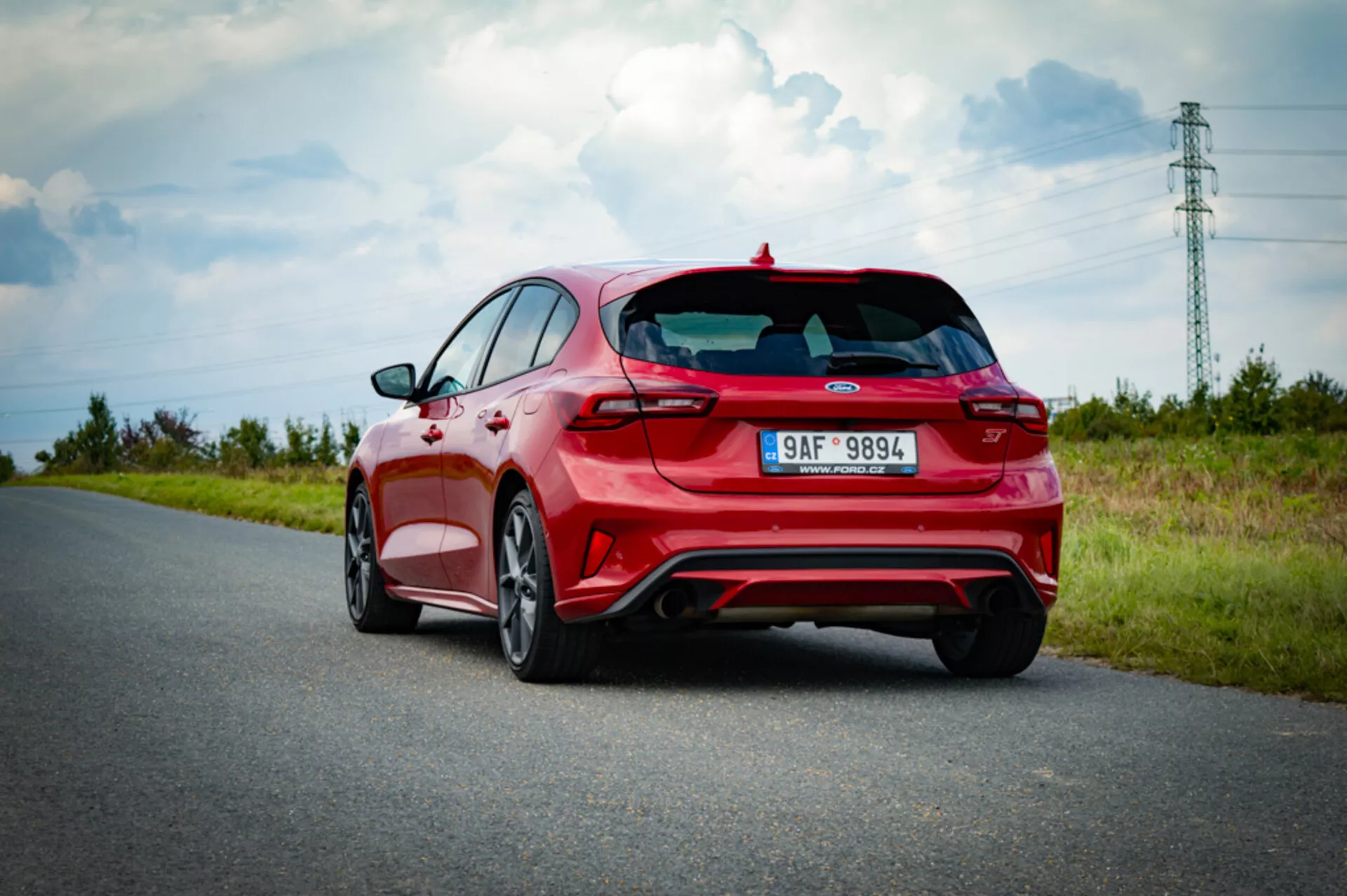 Ford Focus hatchback 2022 con vista posteriore a tre quarti che mostra i fanali posteriori, il lunotto, il trim sportivo con spoiler e doppio scarico, catturata in una giornata di sole