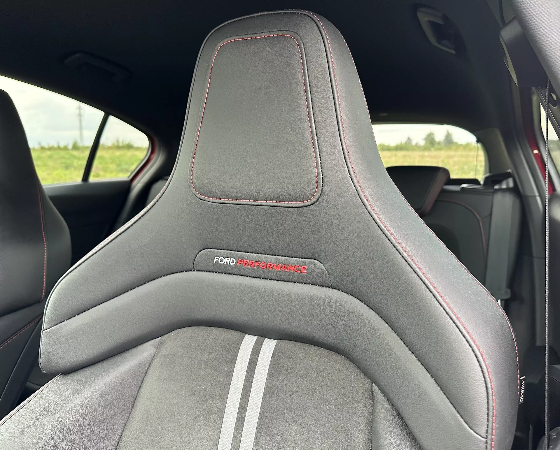 Vista ravvicinata del sedile di una Ford Focus 2022 che mette in evidenza il suo design sportivo con una combinazione di materiali in pelle e camoscio, decorato con il logo 'FORD PERFORMANCE' e dettagli di cuciture rosse.